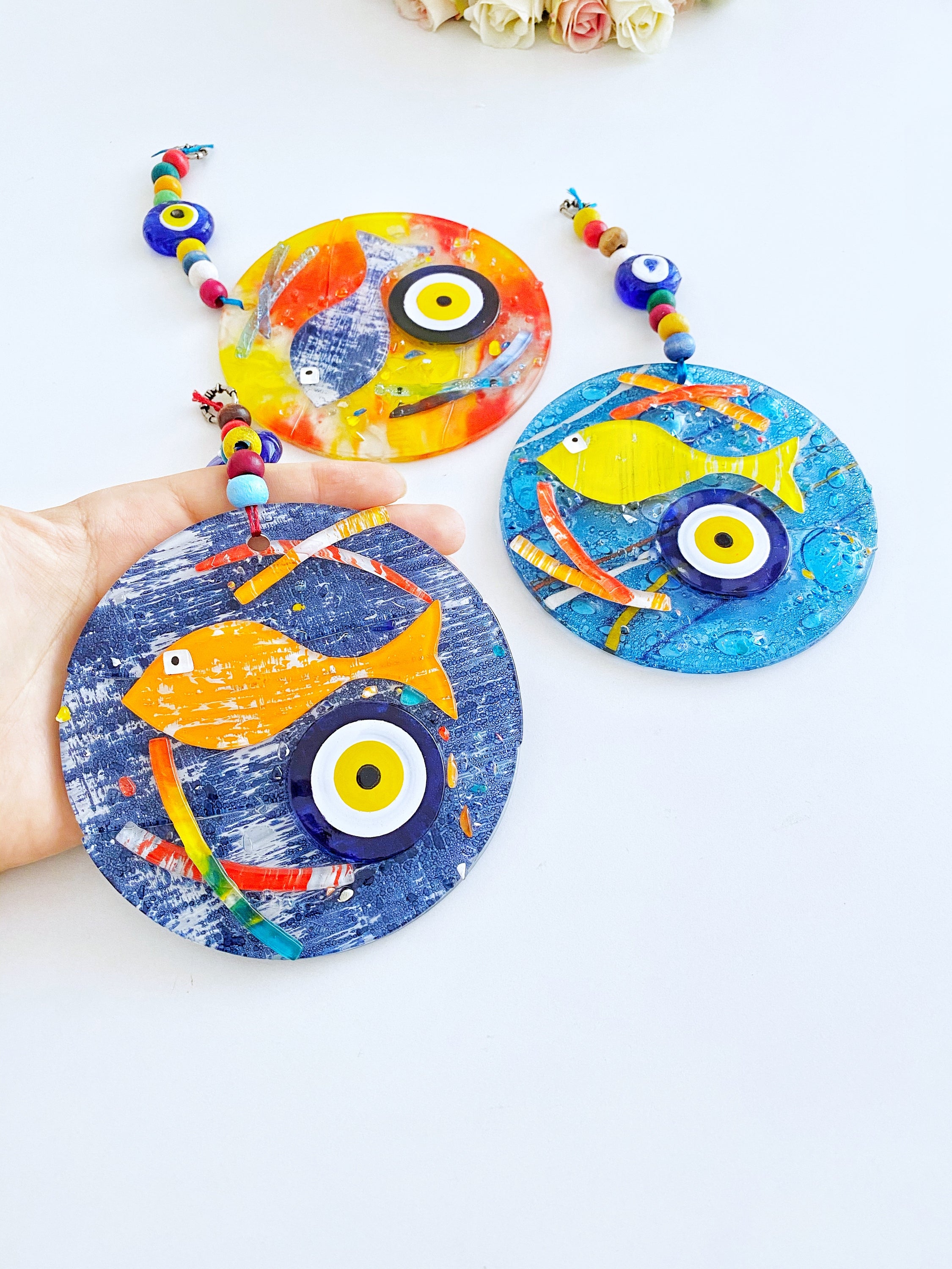 Handmade fused glass Evil Eye wall hanging featuring a fish design, vibrant colors, and unique craftsmanship, measuring 12cm x 12cm.