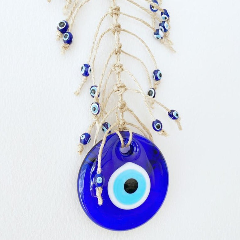 Handmade blue evil eye wall hanging featuring intricate macrame design and a large evil eye bead, perfect for home decor.