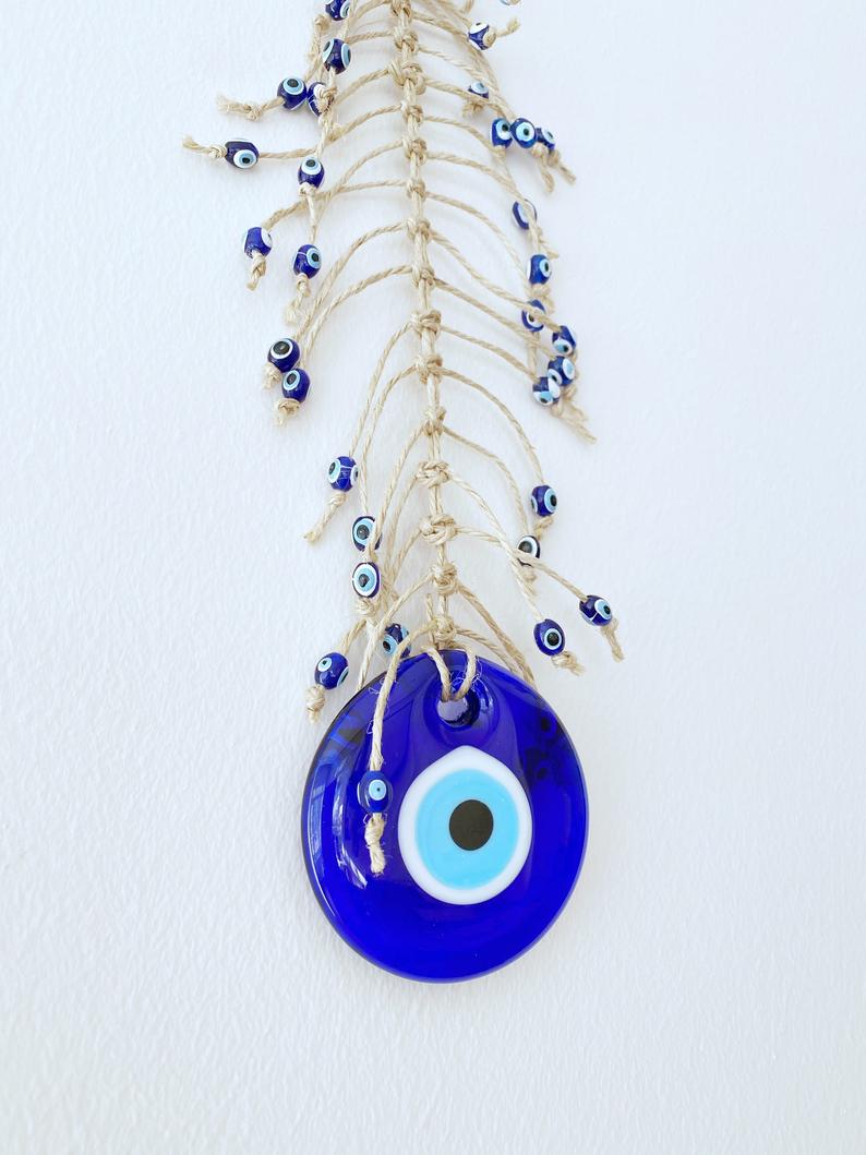 Handmade blue evil eye wall hanging featuring intricate macrame design and a large evil eye bead, perfect for home decor.