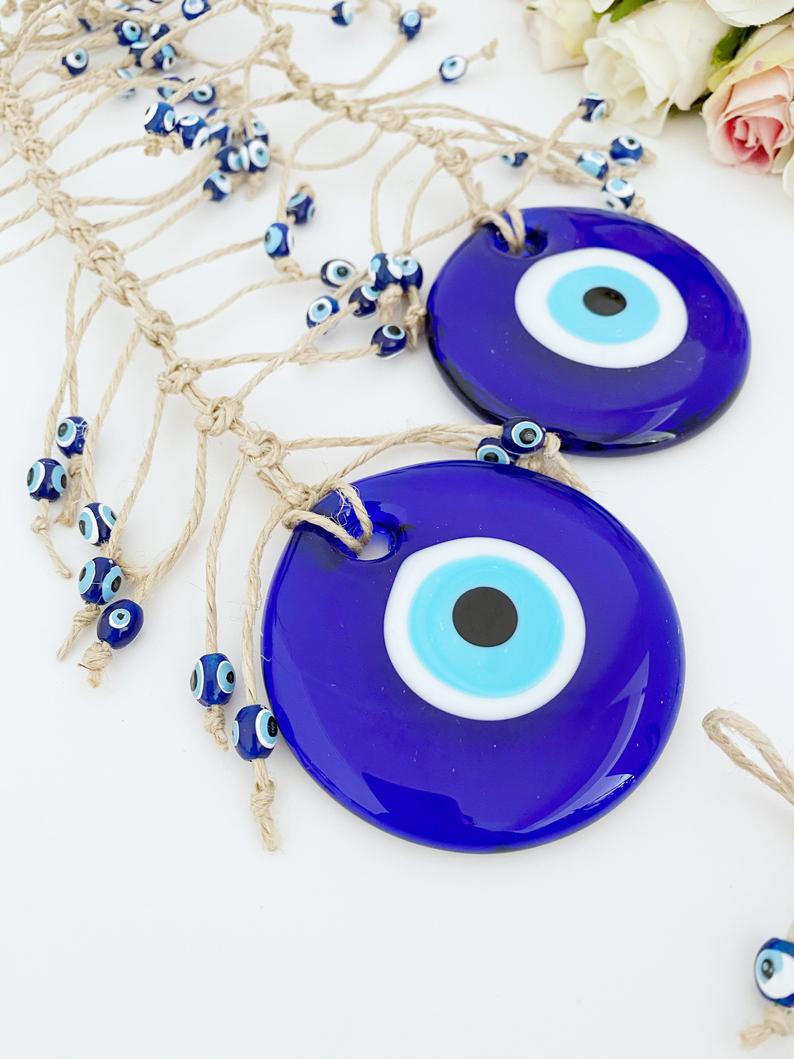 Handmade blue evil eye wall hanging featuring intricate macrame design and a large evil eye bead, perfect for home decor.