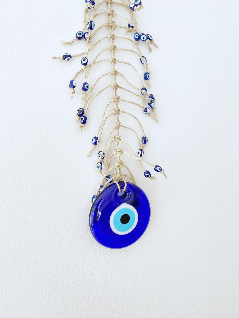 Handmade blue evil eye wall hanging featuring intricate macrame design and a large evil eye bead, perfect for home decor.