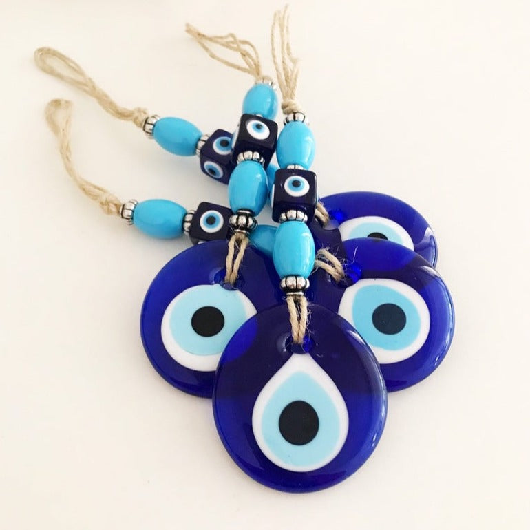 Handmade evil eye wall hanging featuring a large blue evil eye bead and turquoise beads, perfect for home decor and protection.