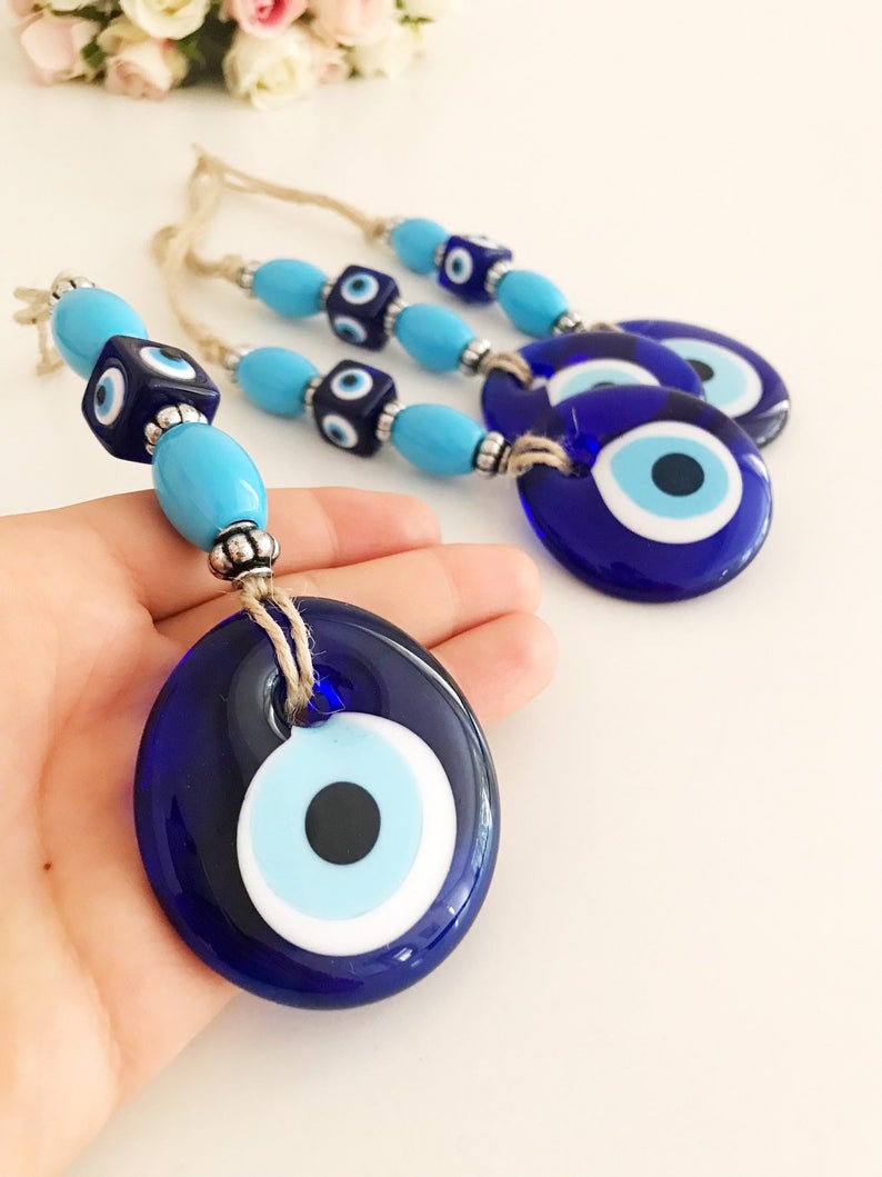 Handmade evil eye wall hanging featuring a large blue evil eye bead and turquoise beads, perfect for home decor and protection.