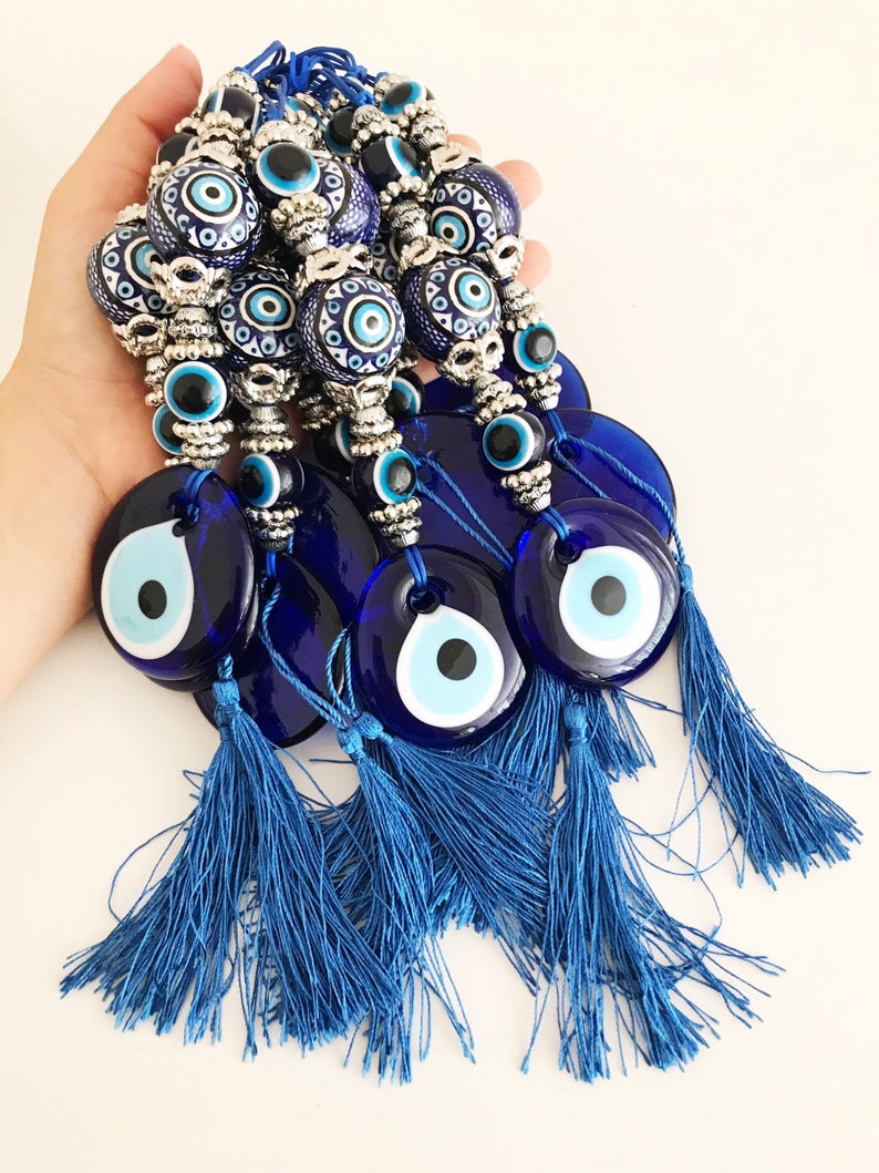 Handmade evil eye wall hanging featuring a blue ceramic evil eye bead and a ceramic ball, measuring 33cm in length.