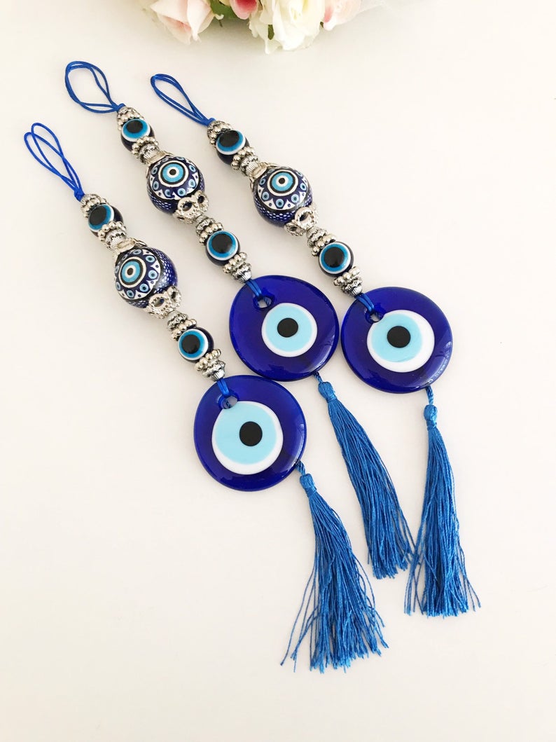 Handmade evil eye wall hanging featuring a blue ceramic evil eye bead and a ceramic ball, measuring 33cm in length.