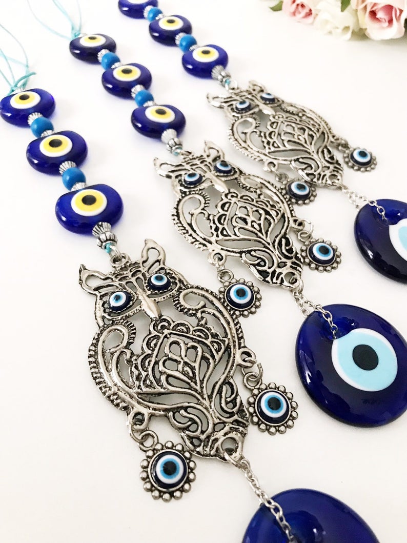 Handmade evil eye wall hanging featuring a metal owl decoration, showcasing unique craftsmanship and vibrant colors.