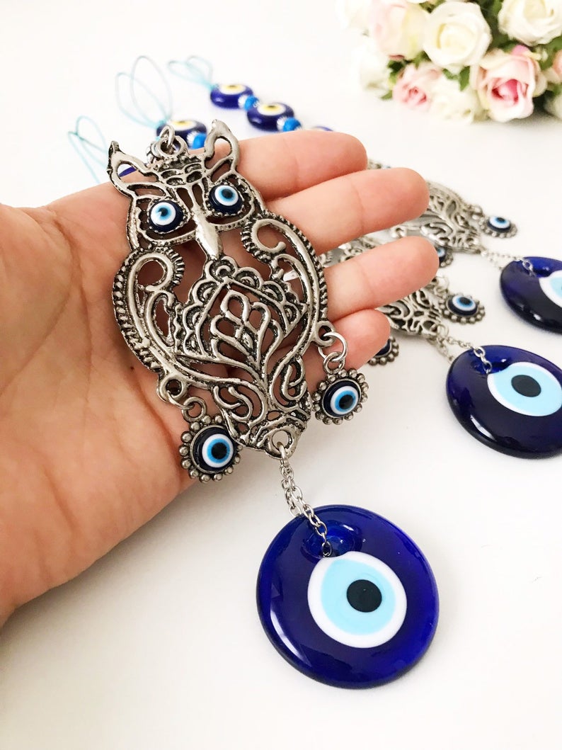 Handmade evil eye wall hanging featuring a metal owl decoration, showcasing unique craftsmanship and vibrant colors.