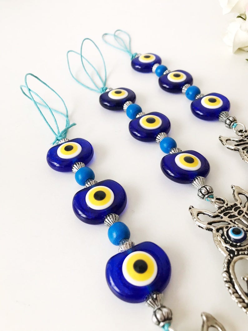 Handmade evil eye wall hanging featuring a metal owl decoration, showcasing unique craftsmanship and vibrant colors.