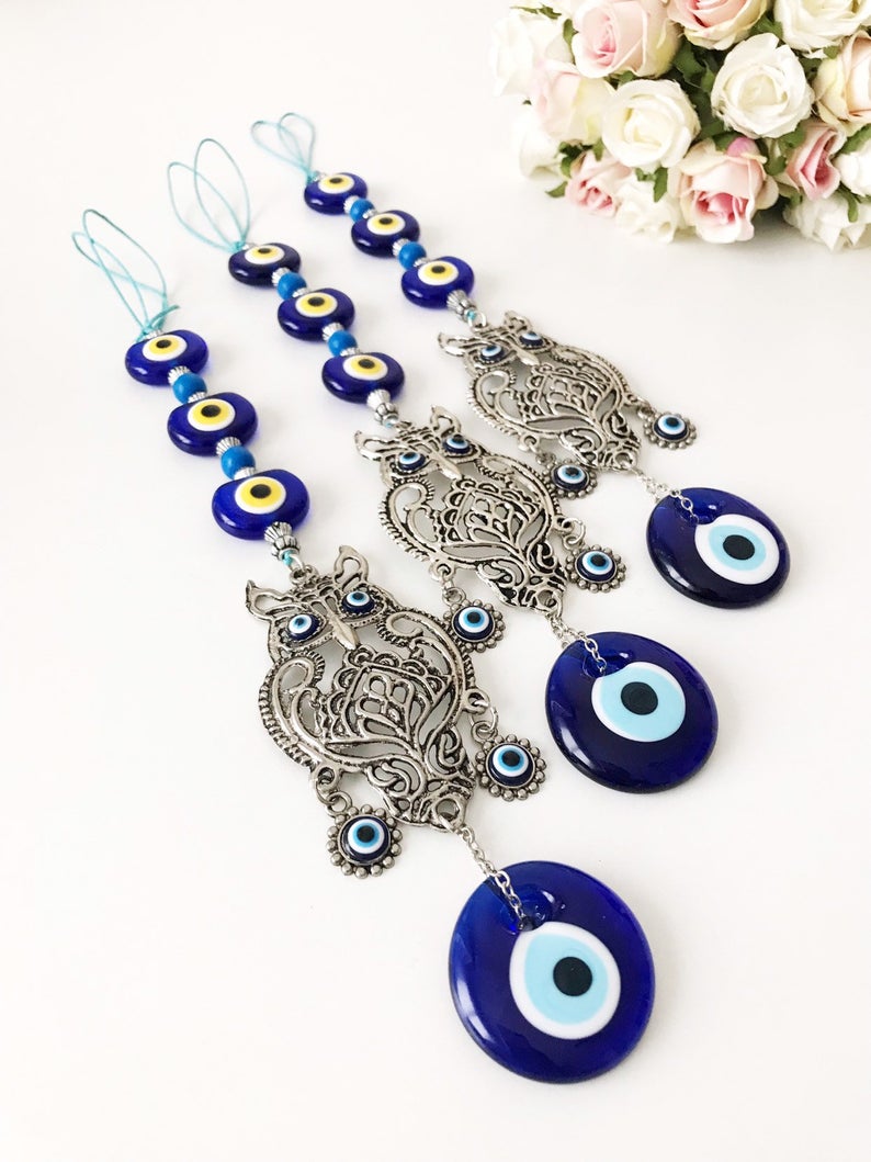 Handmade evil eye wall hanging featuring a metal owl decoration, showcasing unique craftsmanship and vibrant colors.