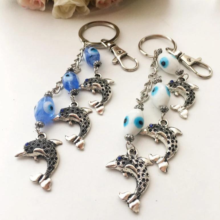 Evileye Dolphin keychain featuring glass evil eye beads in white and blue, with a silver dolphin charm, perfect for keys or bags.