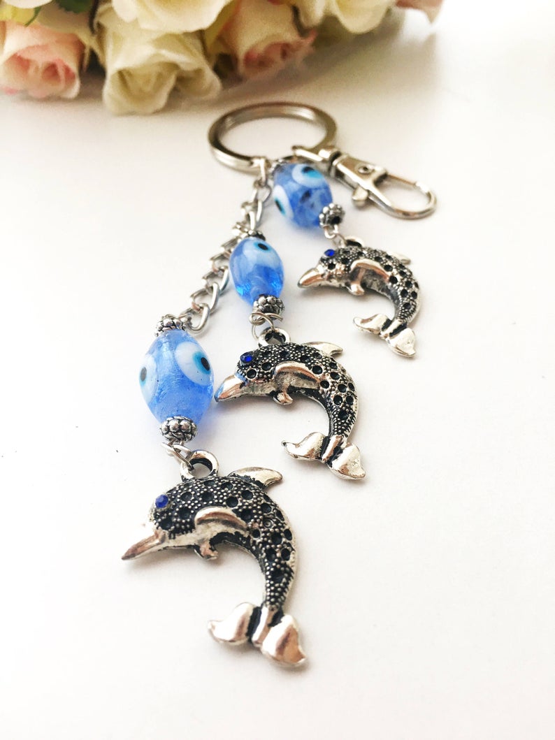 Evileye Dolphin keychain featuring glass evil eye beads in white and blue, with a silver dolphin charm, perfect for keys or bags.