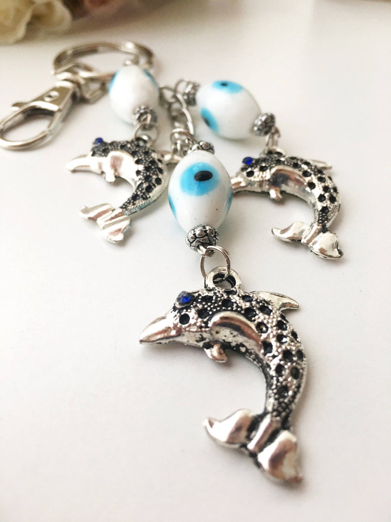 Evileye Dolphin keychain featuring glass evil eye beads in white and blue, with a silver dolphin charm, perfect for keys or bags.