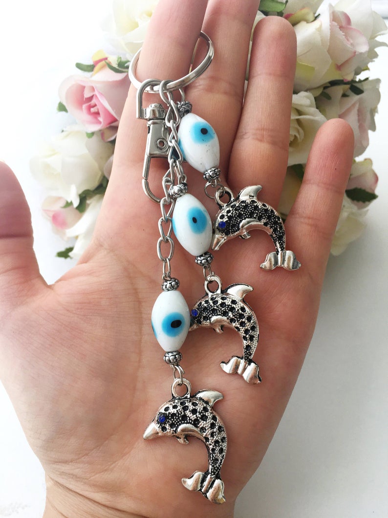 Evileye Dolphin keychain featuring glass evil eye beads in white and blue, with a silver dolphin charm, perfect for keys or bags.