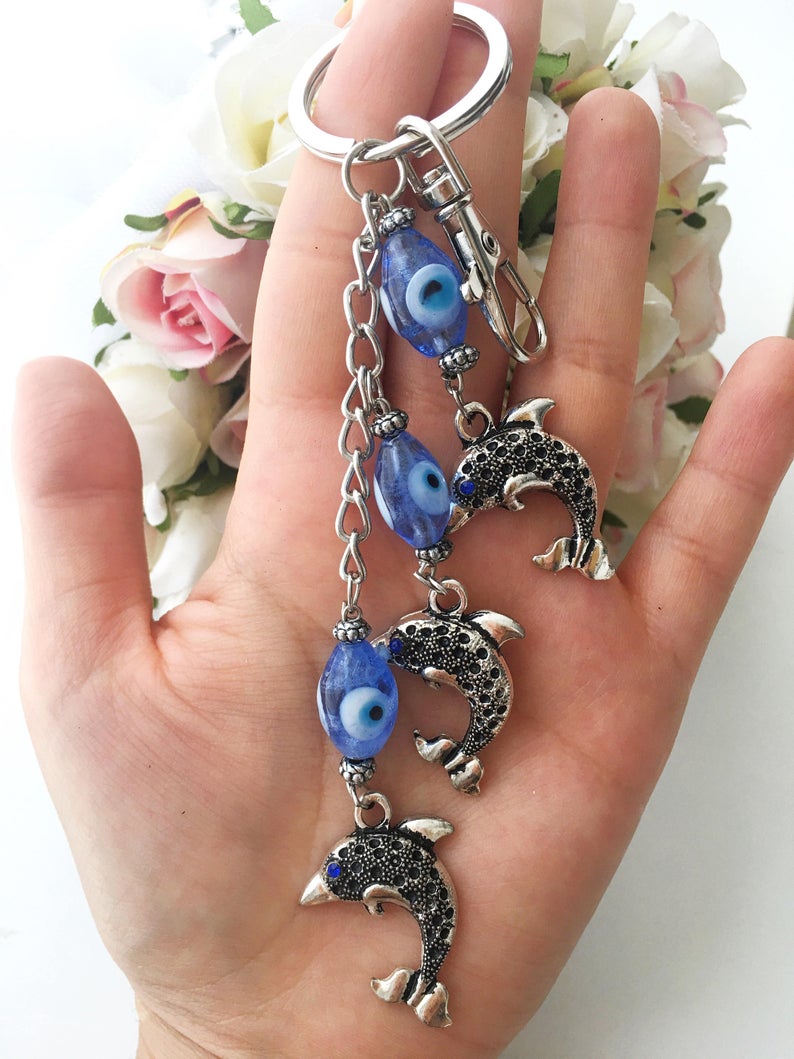 Evileye Dolphin keychain featuring glass evil eye beads in white and blue, with a silver dolphin charm, perfect for keys or bags.