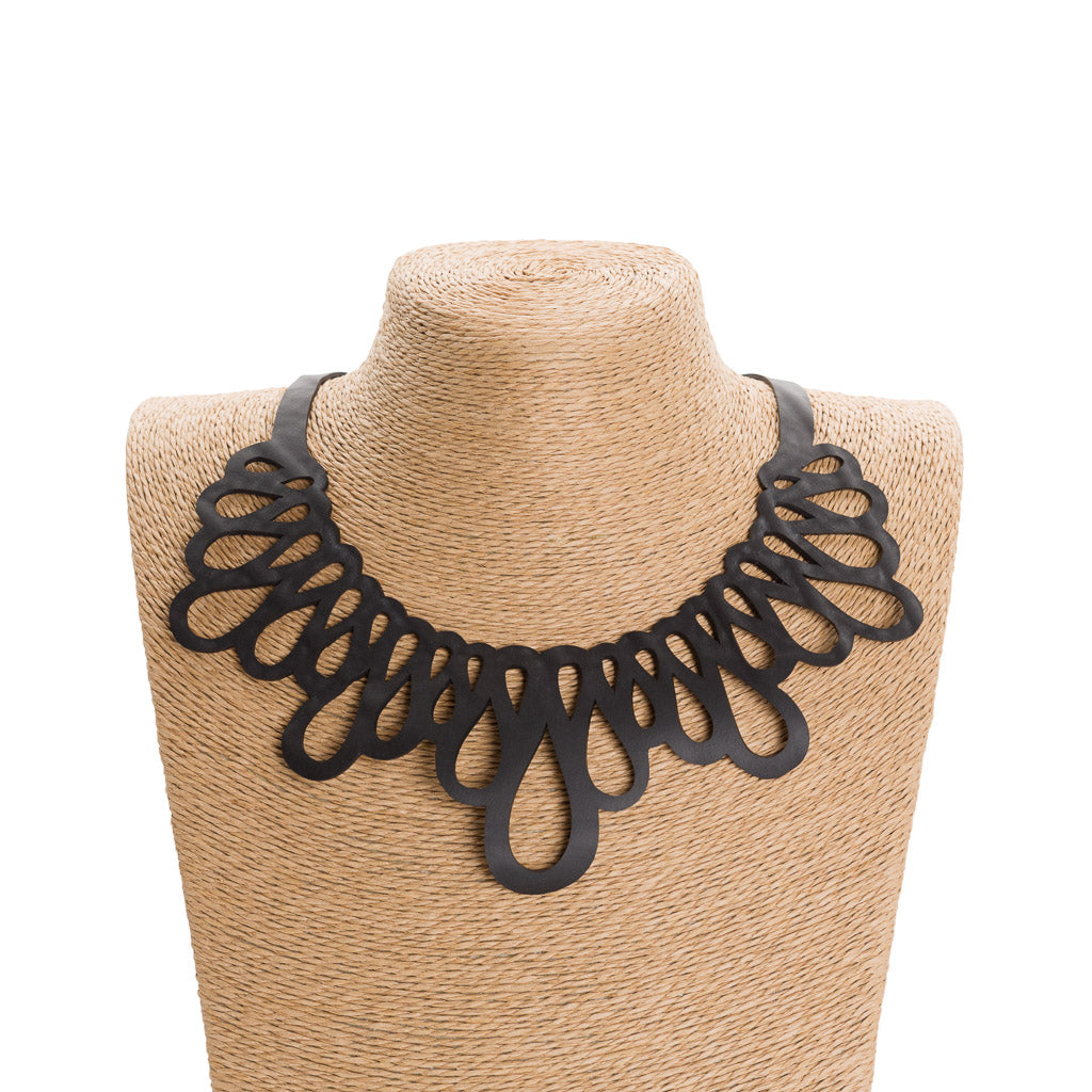 Fall Inner Tube Wave Necklace made from reclaimed rubber, featuring a wave-like design that elegantly frames the neckline.