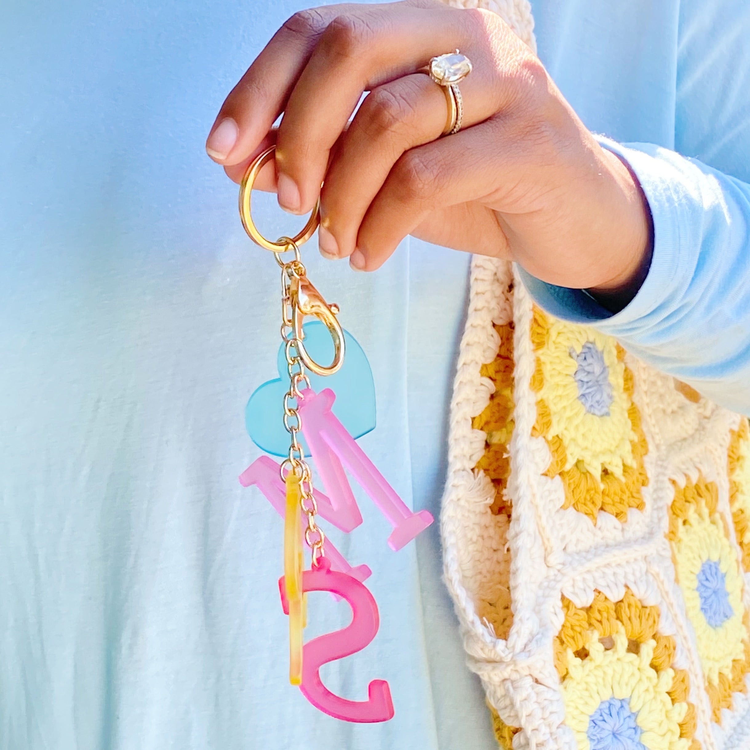 A stylish Favorite Word Jingle Key Chain featuring beautifully cut-out letters and gold tone hardware, perfect for keys or as a bag charm.