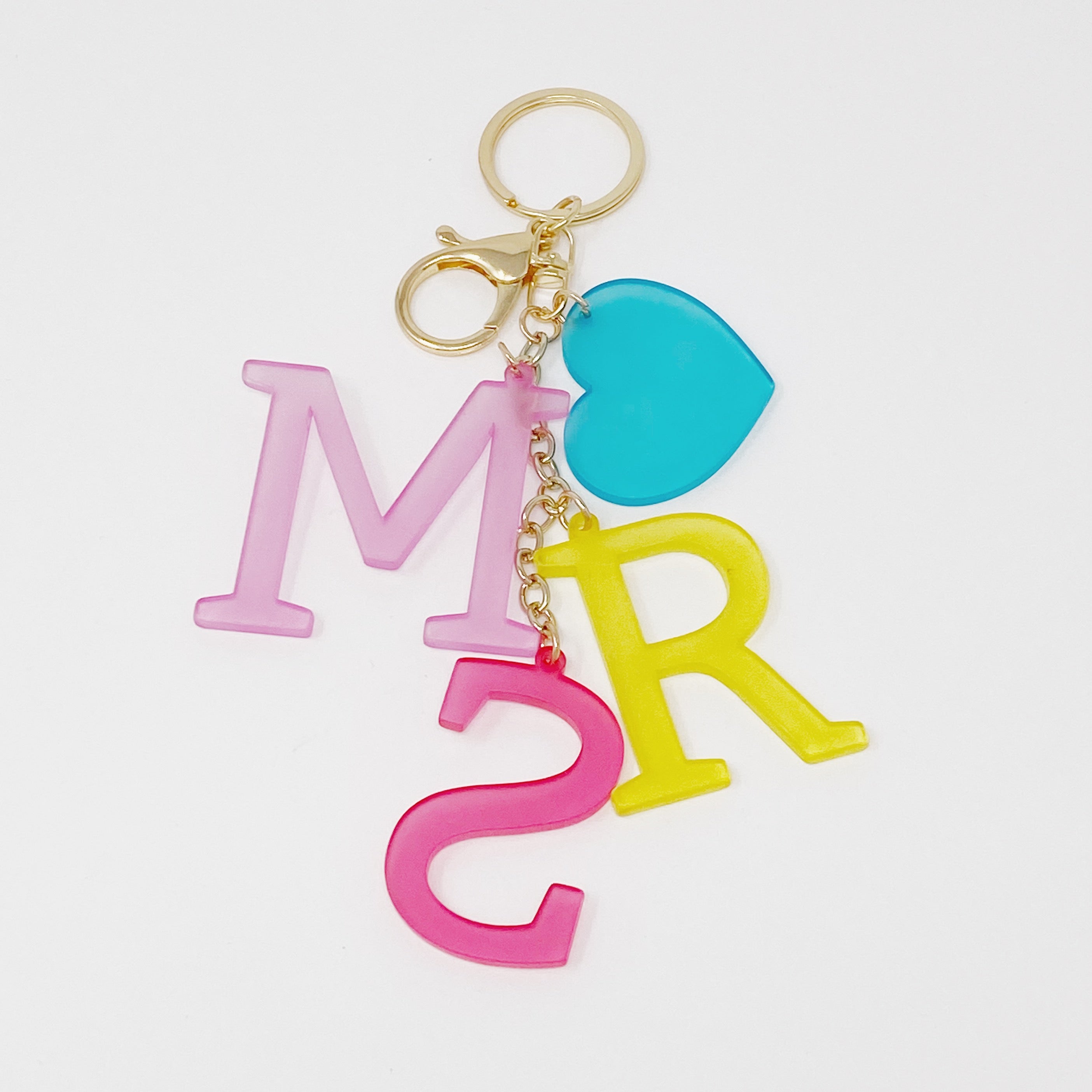 A stylish Favorite Word Jingle Key Chain featuring beautifully cut-out letters and gold tone hardware, perfect for keys or as a bag charm.