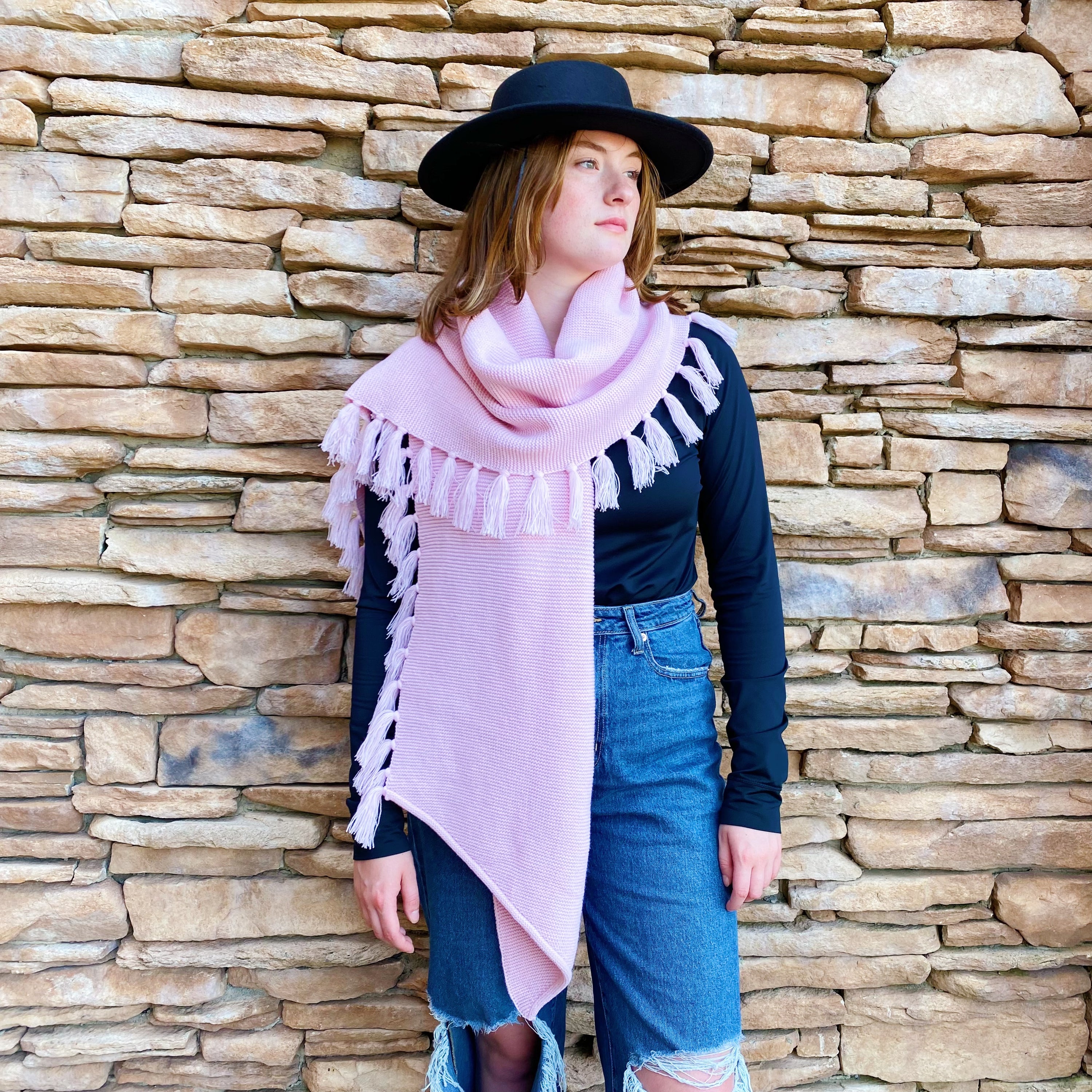 A cozy pink blanket scarf with fringes, showcasing its soft texture and stylish design, perfect for layering.