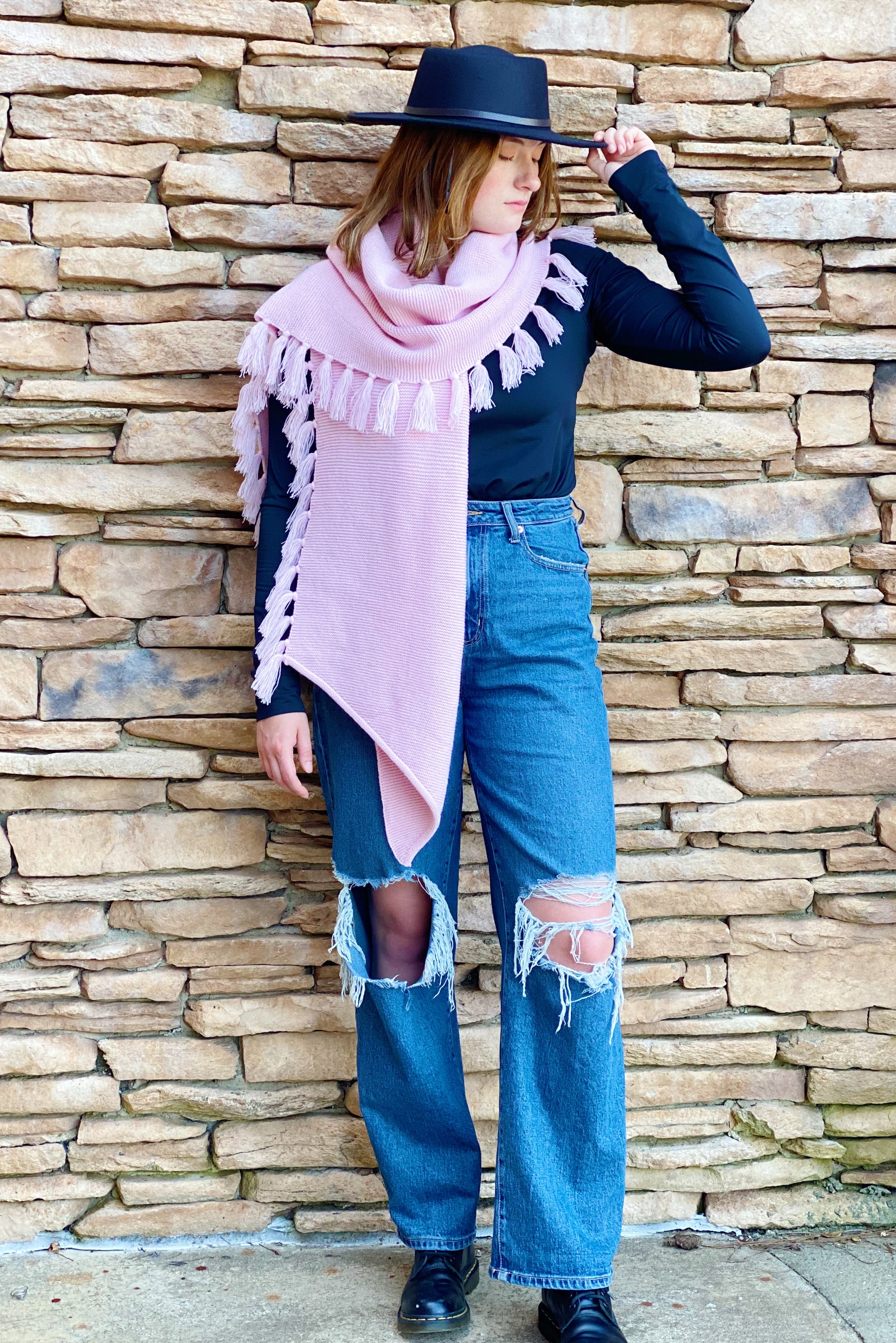 A cozy pink blanket scarf with fringes, showcasing its soft texture and stylish design, perfect for layering.