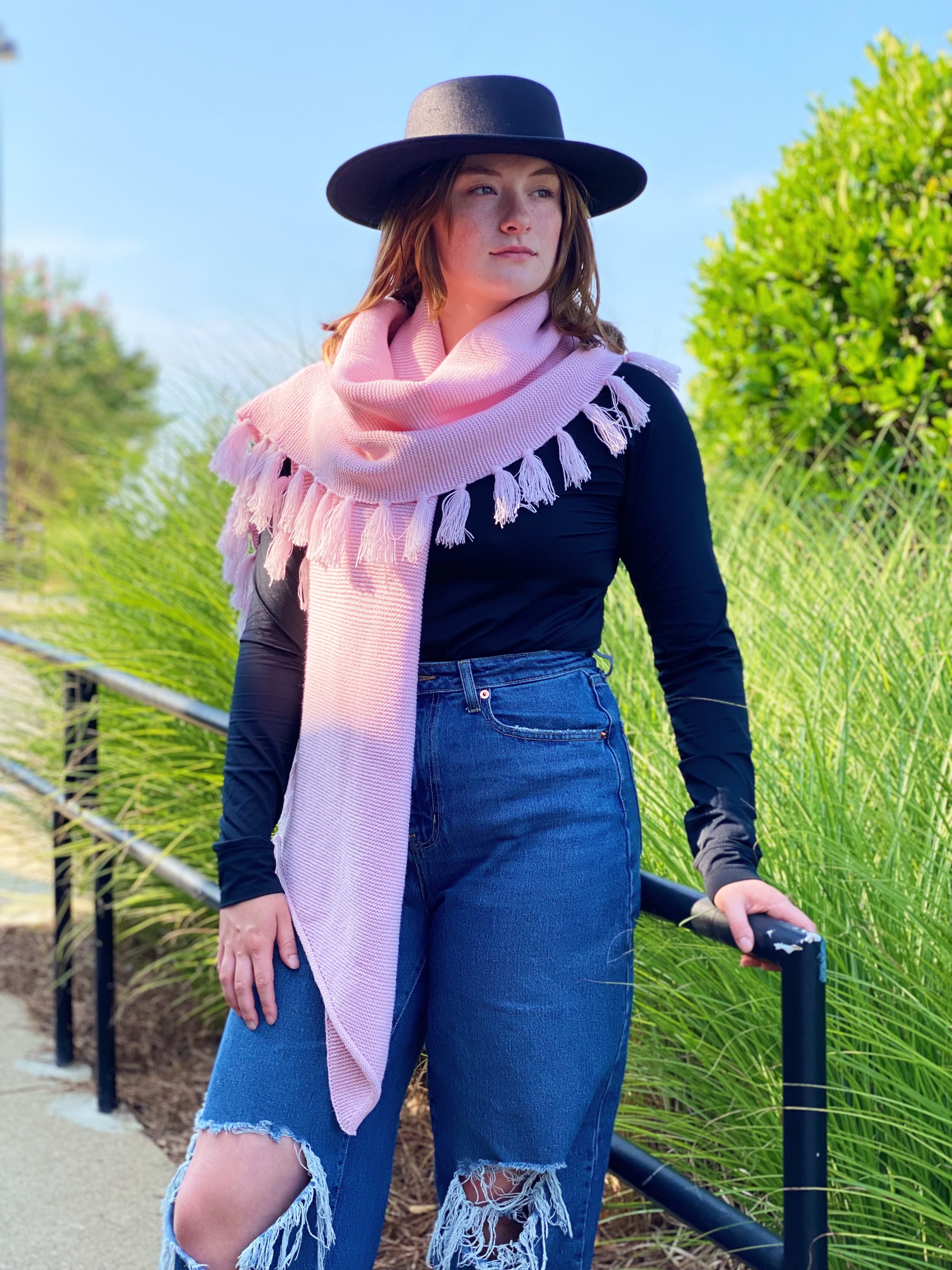 A cozy pink blanket scarf with fringes, showcasing its soft texture and stylish design, perfect for layering.