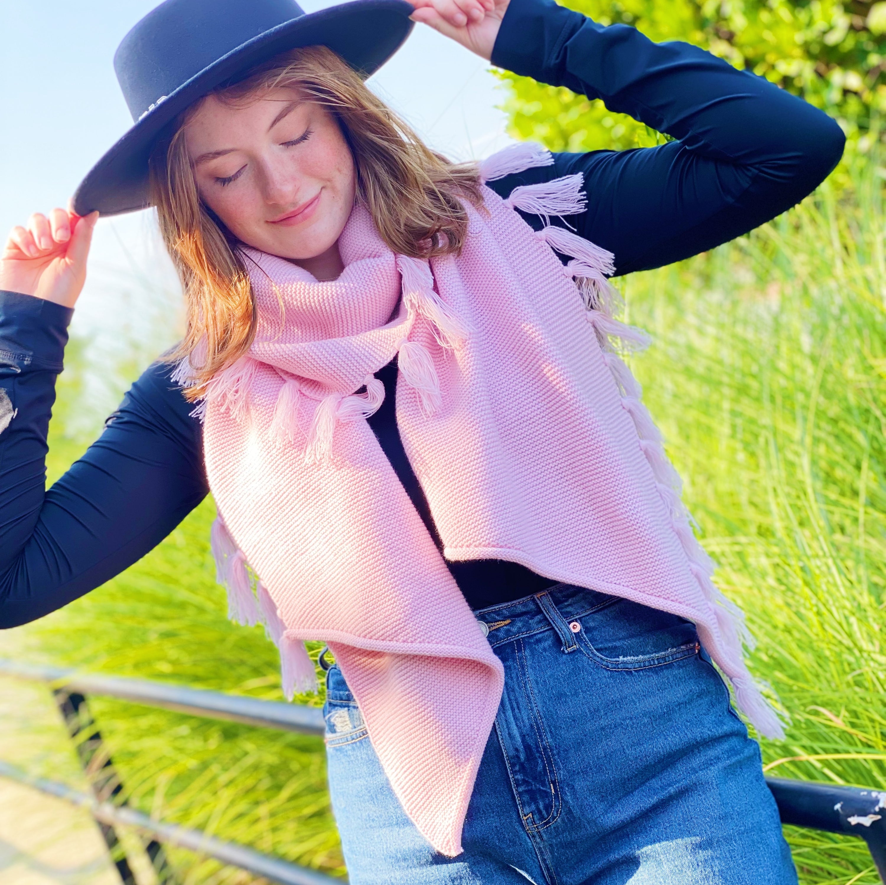 A cozy pink blanket scarf with fringes, showcasing its soft texture and stylish design, perfect for layering.