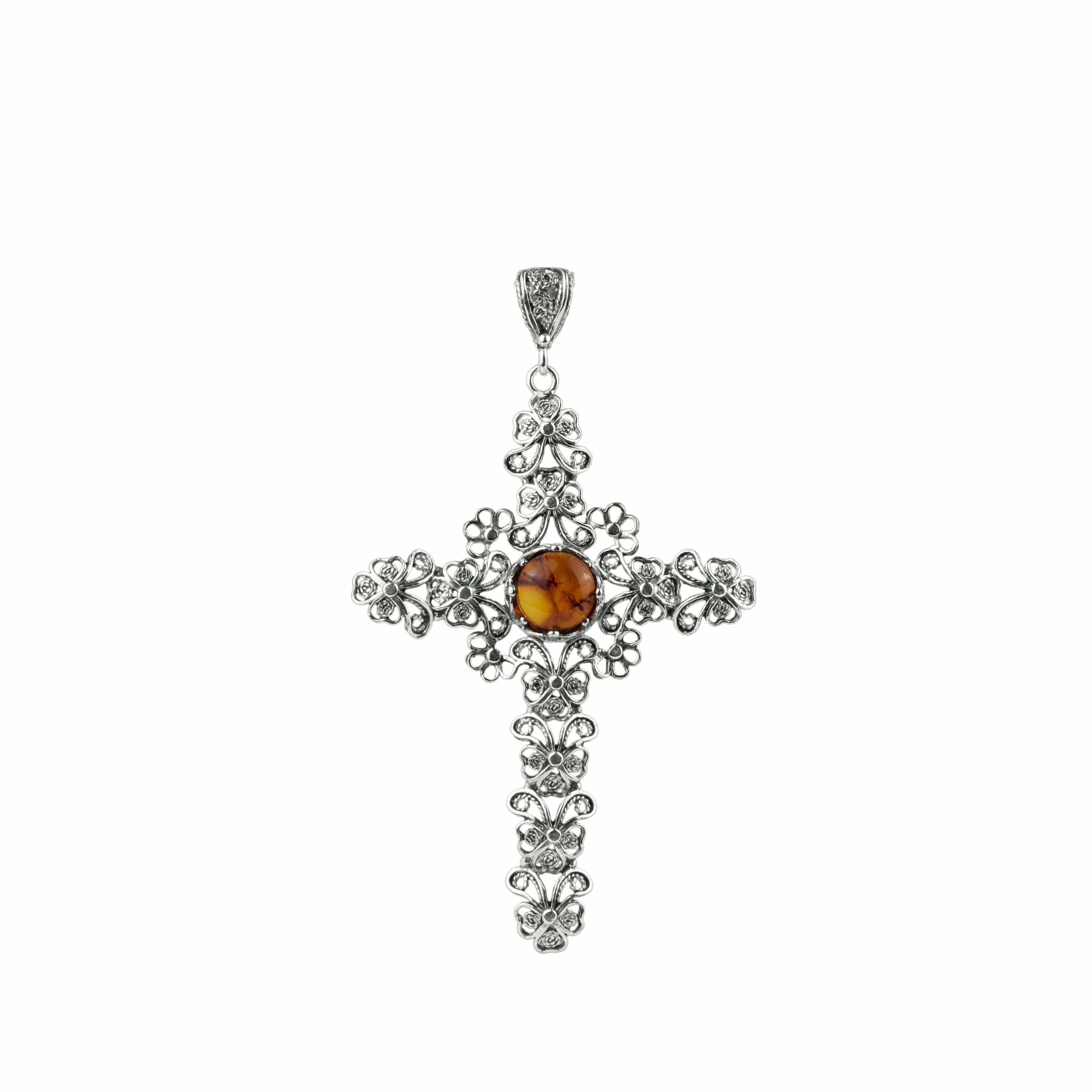 Elegant silver cross pendant necklace featuring intricate filigree design and a round amber stone centerpiece.