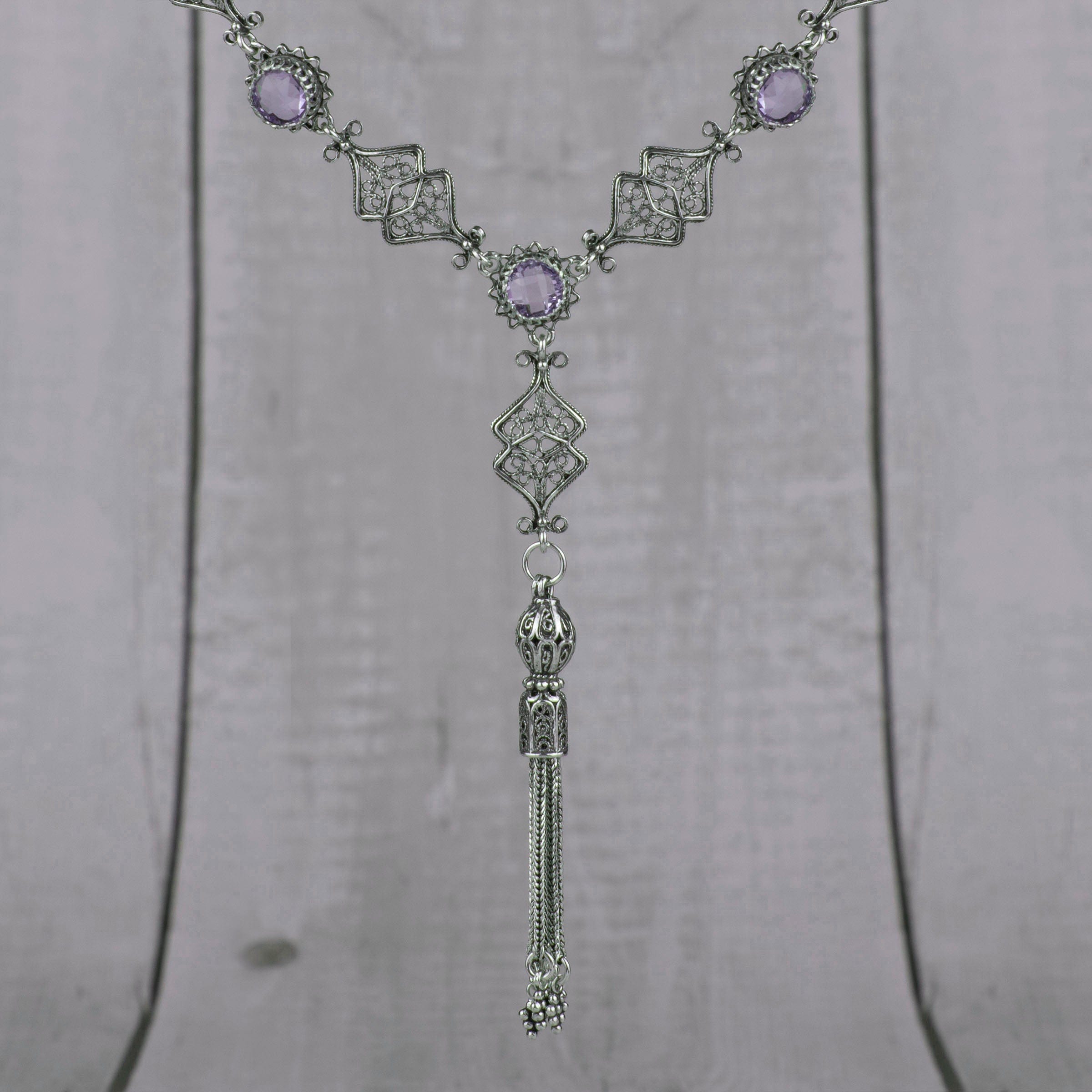 Elegant silver tassel choker necklace featuring filigree design with amethyst and blue topaz gemstones.