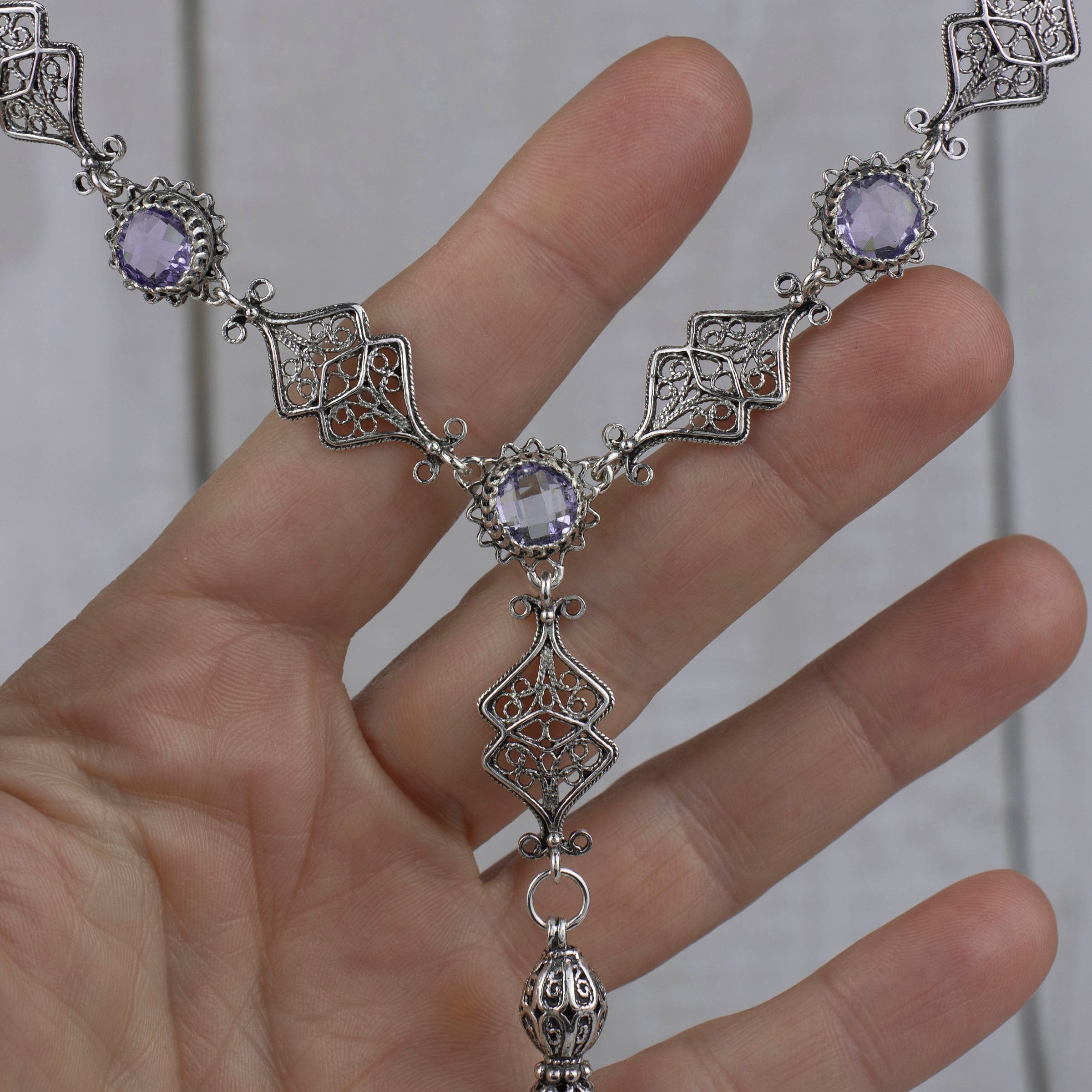 Elegant silver tassel choker necklace featuring filigree design with amethyst and blue topaz gemstones.