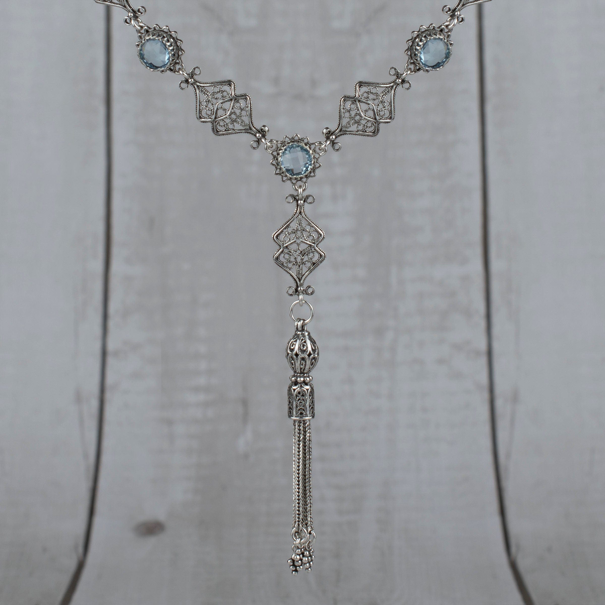 Elegant silver tassel choker necklace featuring filigree design with amethyst and blue topaz gemstones.