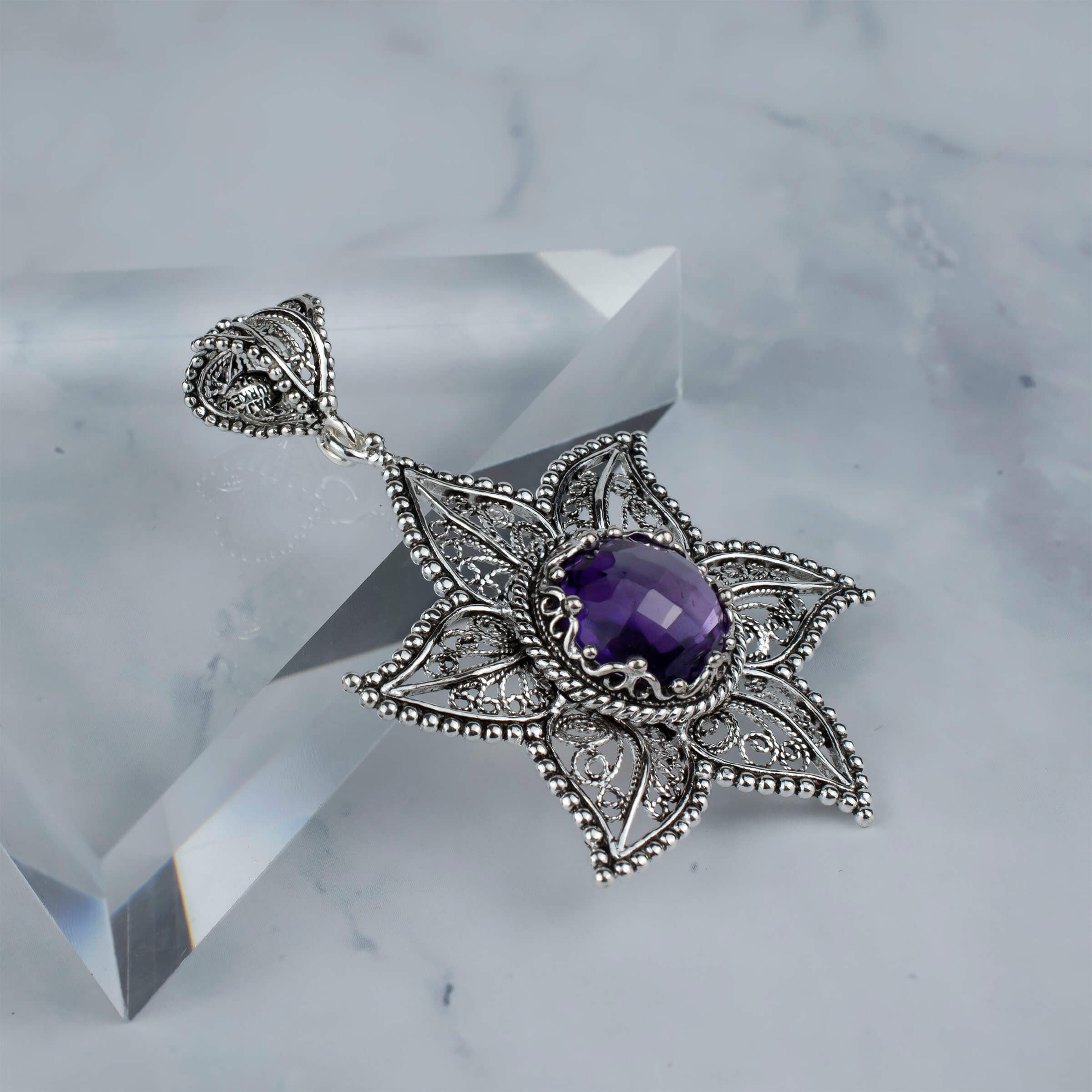 Sterling silver filigree pendant featuring a star design with a 10mm amethyst gemstone, showcasing intricate craftsmanship.