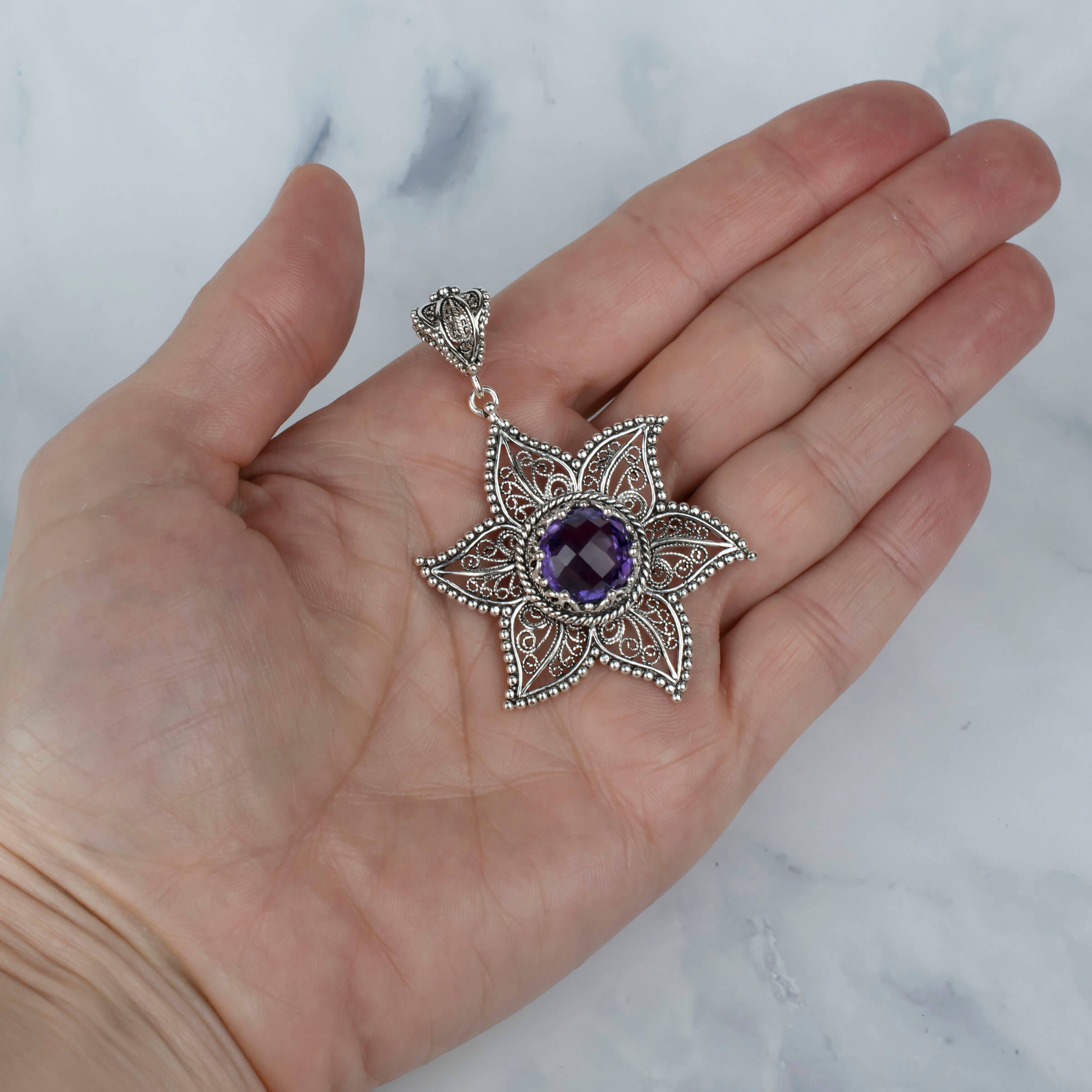 Sterling silver filigree pendant featuring a star design with a 10mm amethyst gemstone, showcasing intricate craftsmanship.