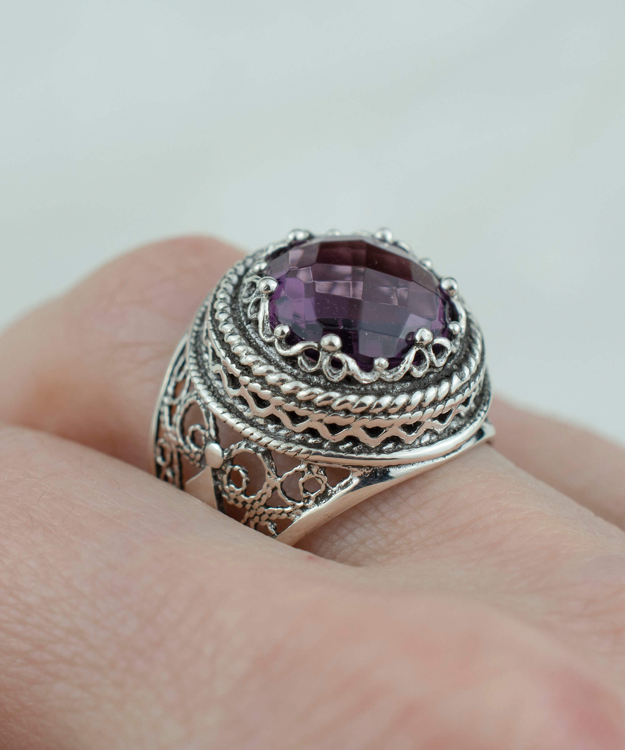 A stunning sterling silver filigree ring featuring a large round-cut amethyst gemstone, elegantly designed with intricate metalwork.