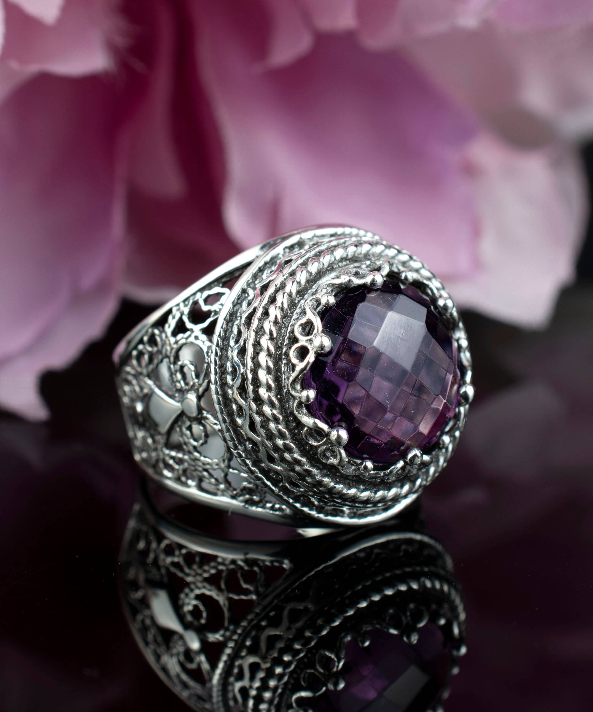 A stunning sterling silver filigree ring featuring a large round-cut amethyst gemstone, elegantly designed with intricate metalwork.