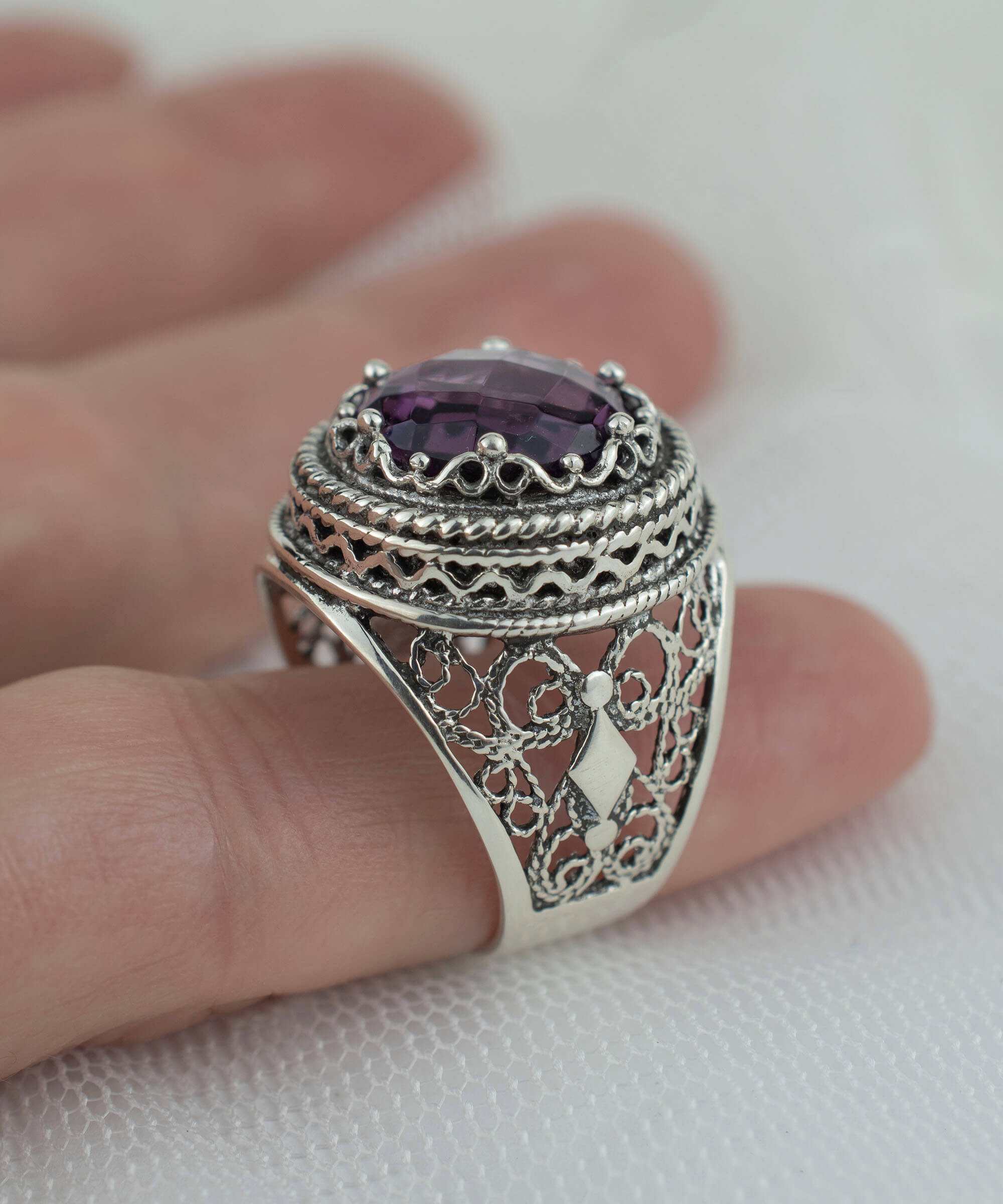 A stunning sterling silver filigree ring featuring a large round-cut amethyst gemstone, elegantly designed with intricate metalwork.