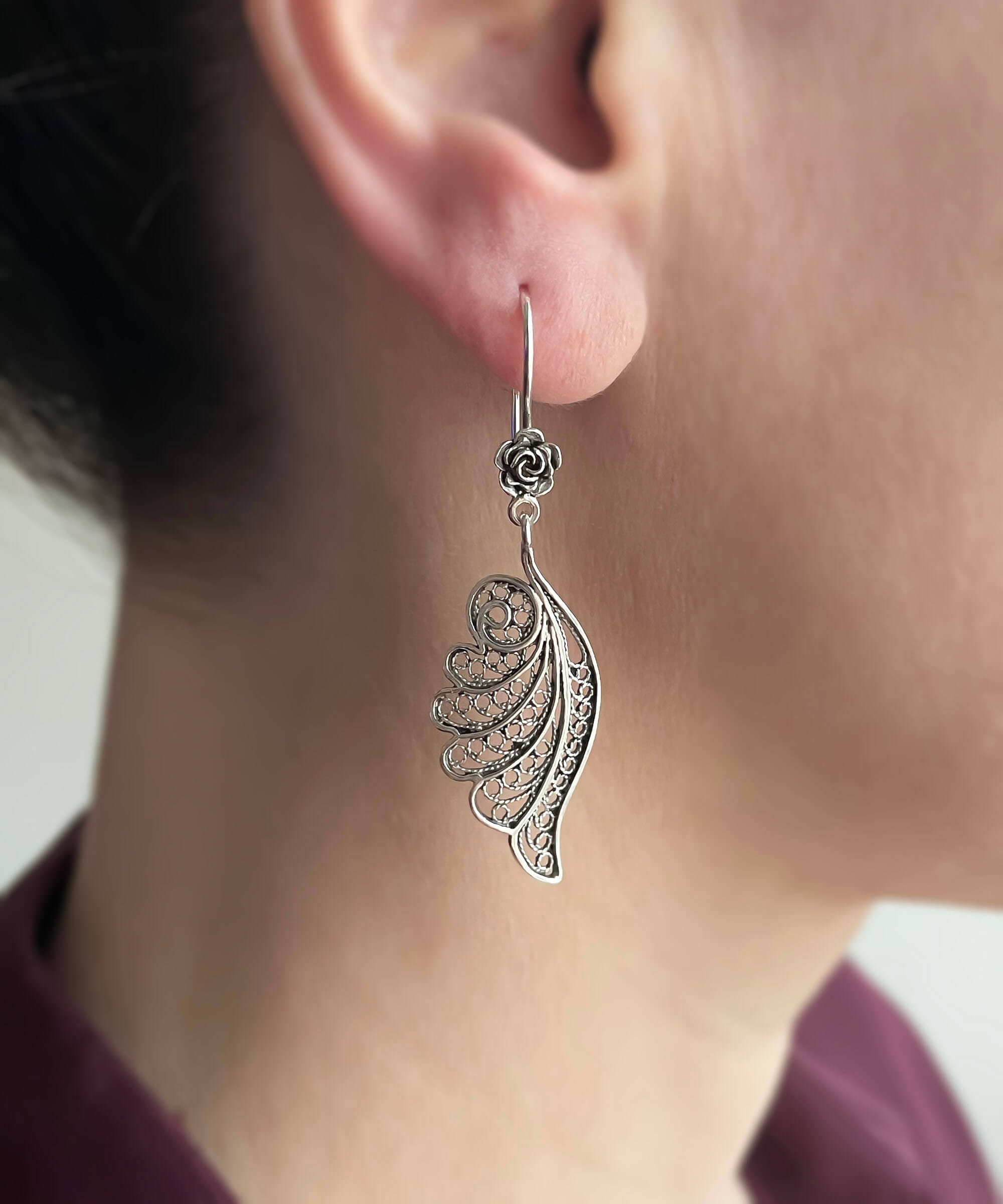 Elegant silver dangle drop earrings featuring intricate filigree angel wings design, handmade from high-quality 925 sterling silver.