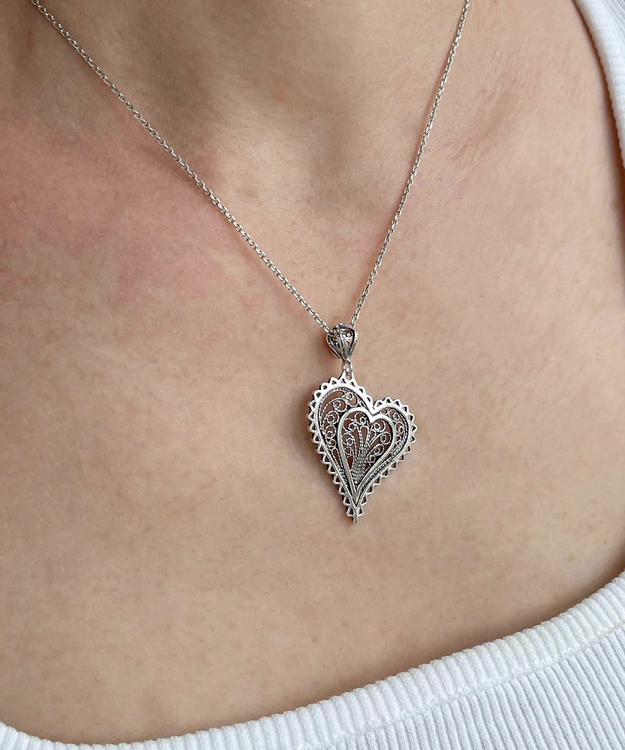 Elegant 925 Sterling Silver filigree heart pendant necklace with asymmetric design, displayed on a soft velvet background.