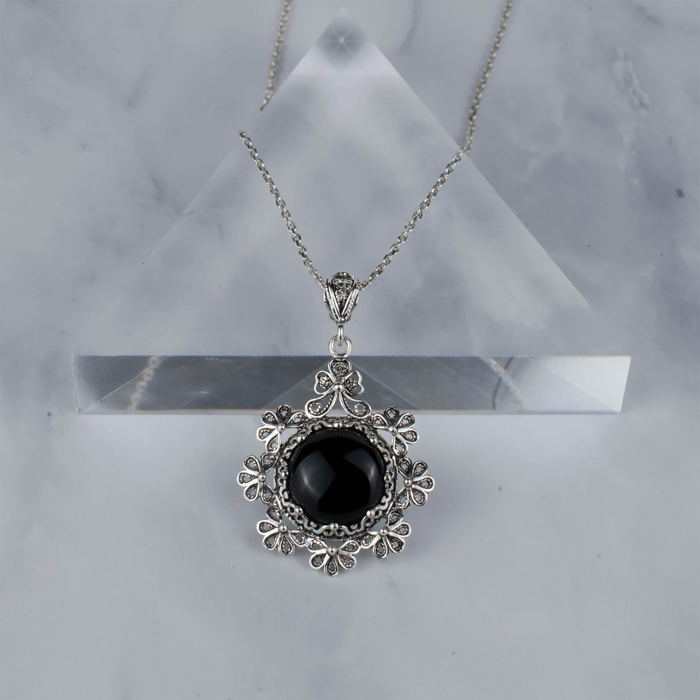 Sterling silver floral pendant featuring a black onyx gemstone, showcasing intricate filigree art design.