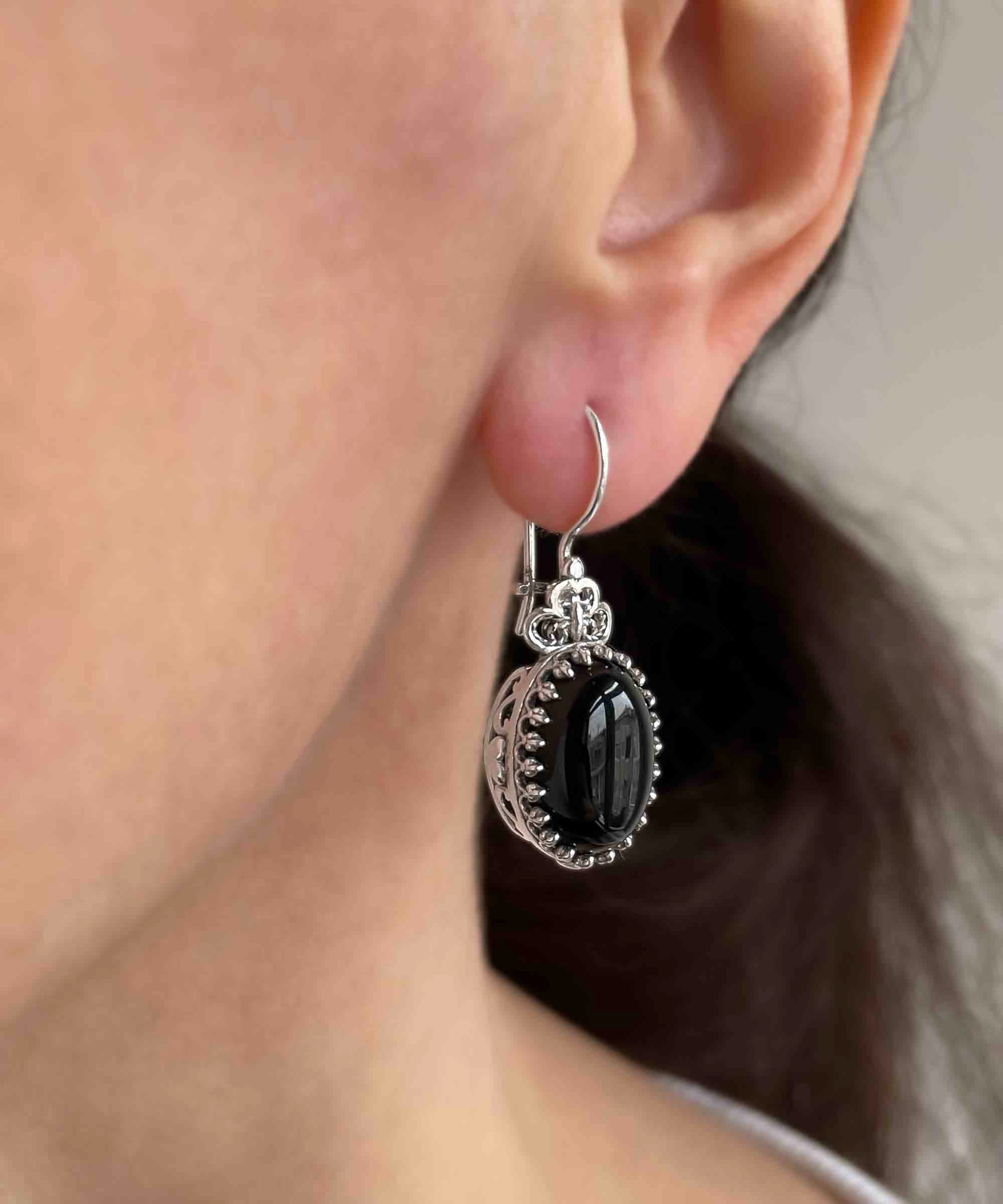 Elegant silver oval drop earrings featuring intricate filigree heart design and black onyx gemstone.