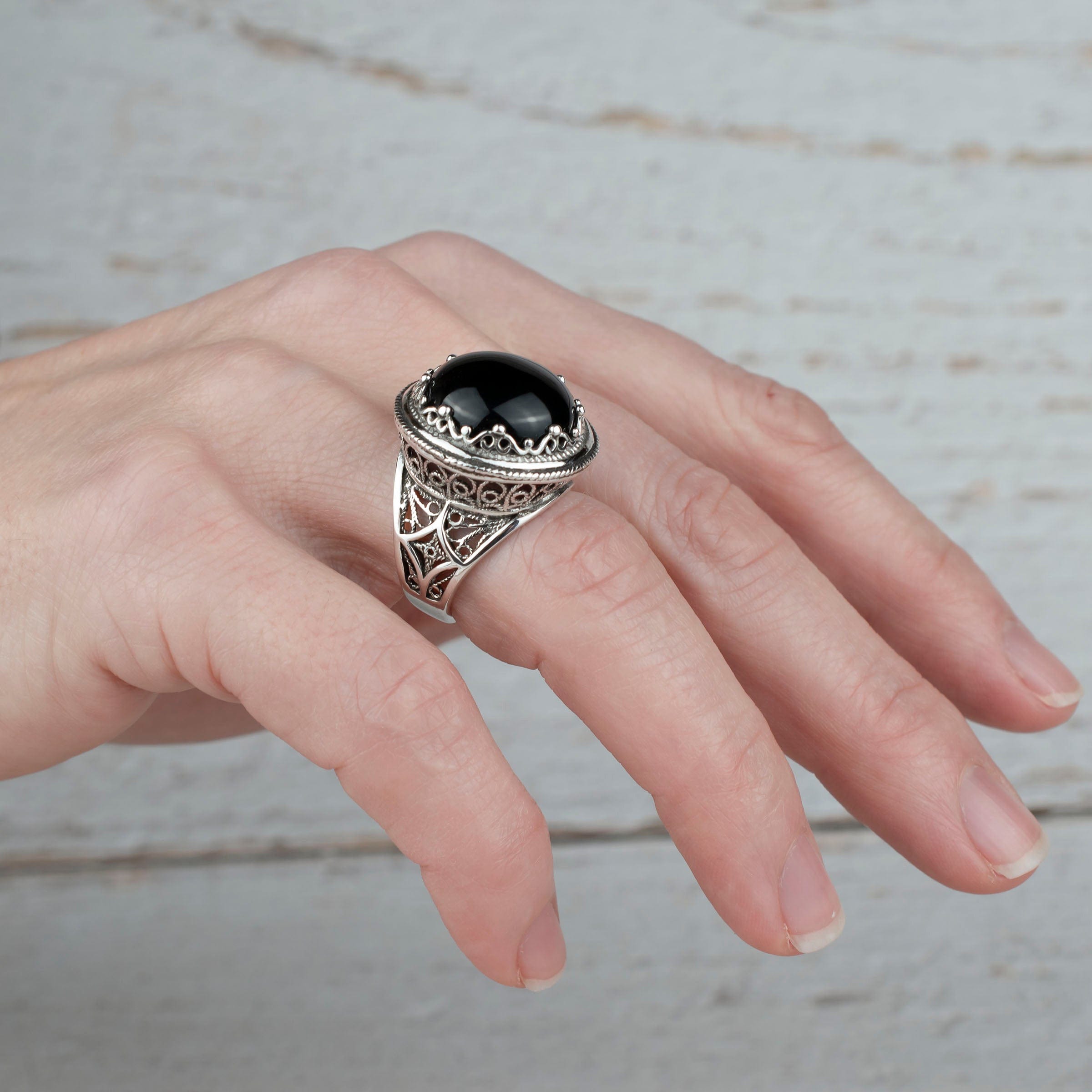 A bold statement ring featuring a black onyx gemstone set in intricate sterling silver filigree design, showcasing elegance and craftsmanship.