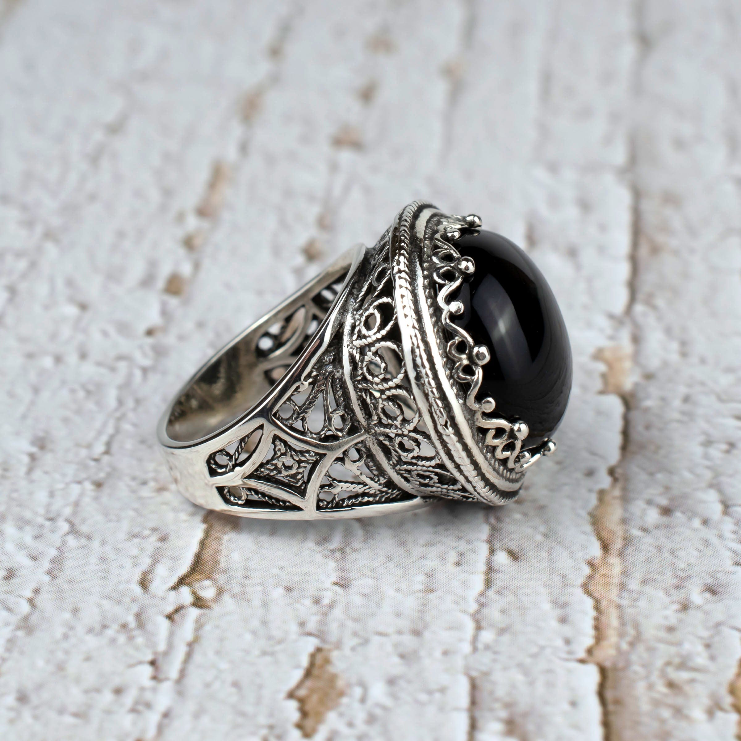 A bold statement ring featuring a black onyx gemstone set in intricate sterling silver filigree design, showcasing elegance and craftsmanship.