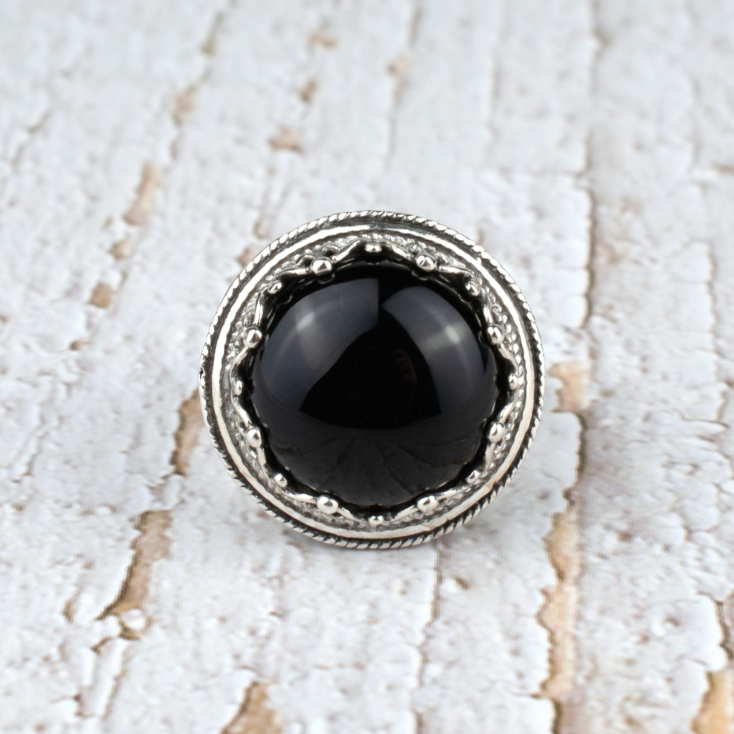 A bold statement ring featuring a black onyx gemstone set in intricate sterling silver filigree design, showcasing elegance and craftsmanship.