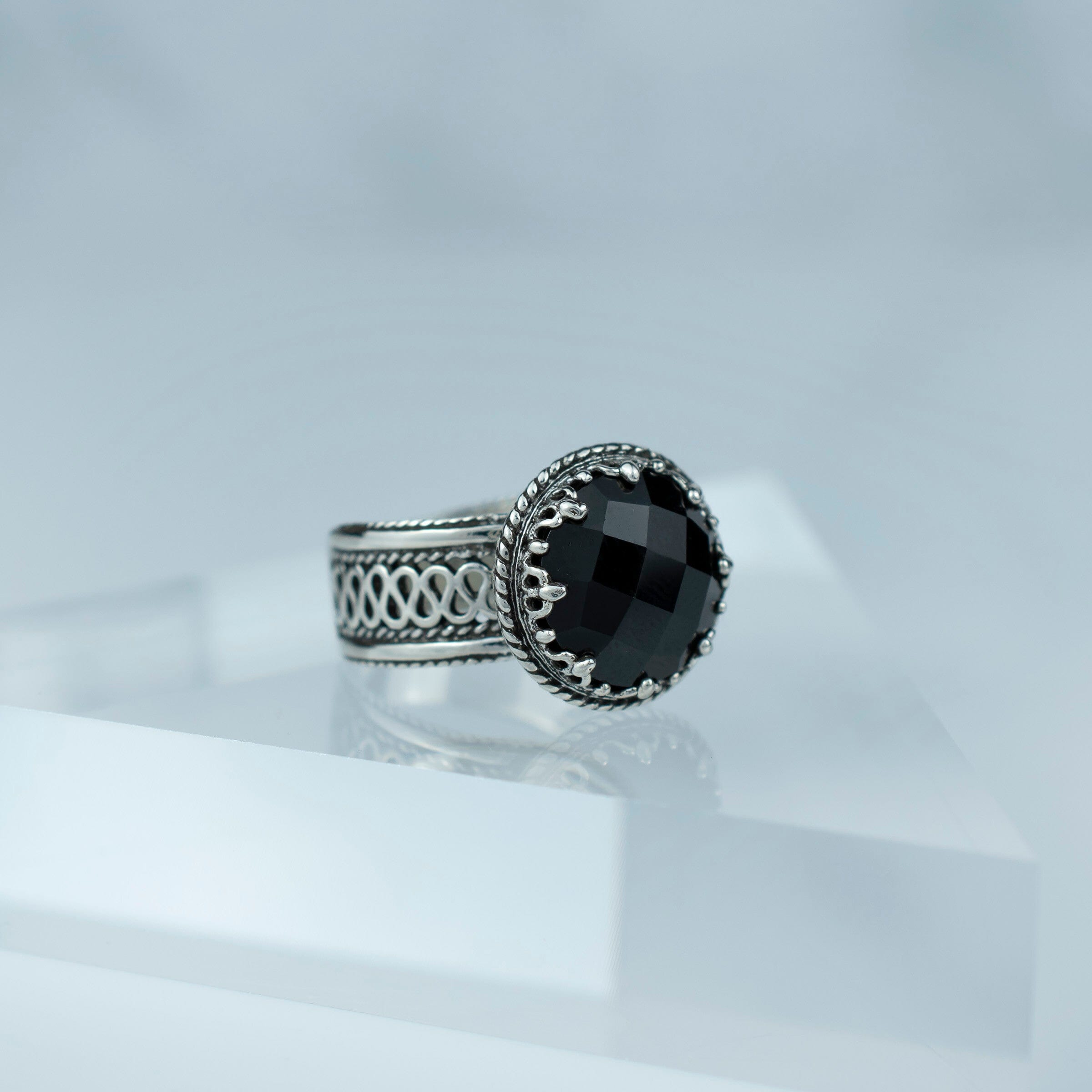 Elegant sterling silver cocktail ring featuring a black onyx gemstone with intricate filigree design.