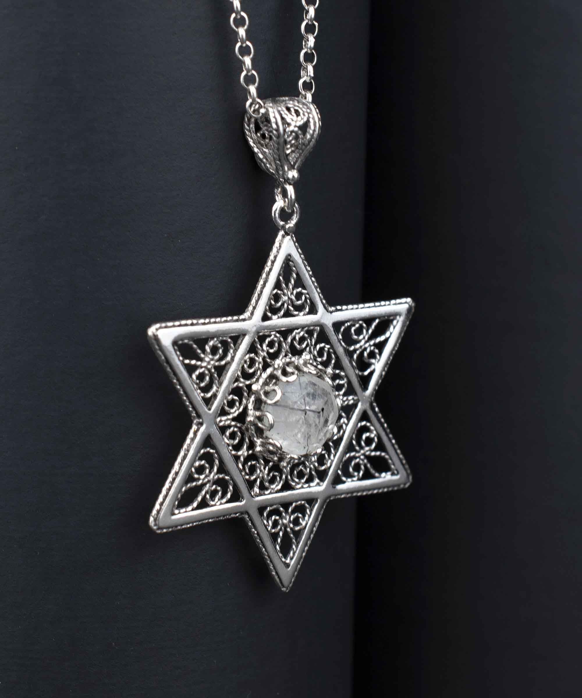 Handcrafted silver pendant featuring a black rutile gemstone in the shape of the Star of David, showcasing intricate filigree art.