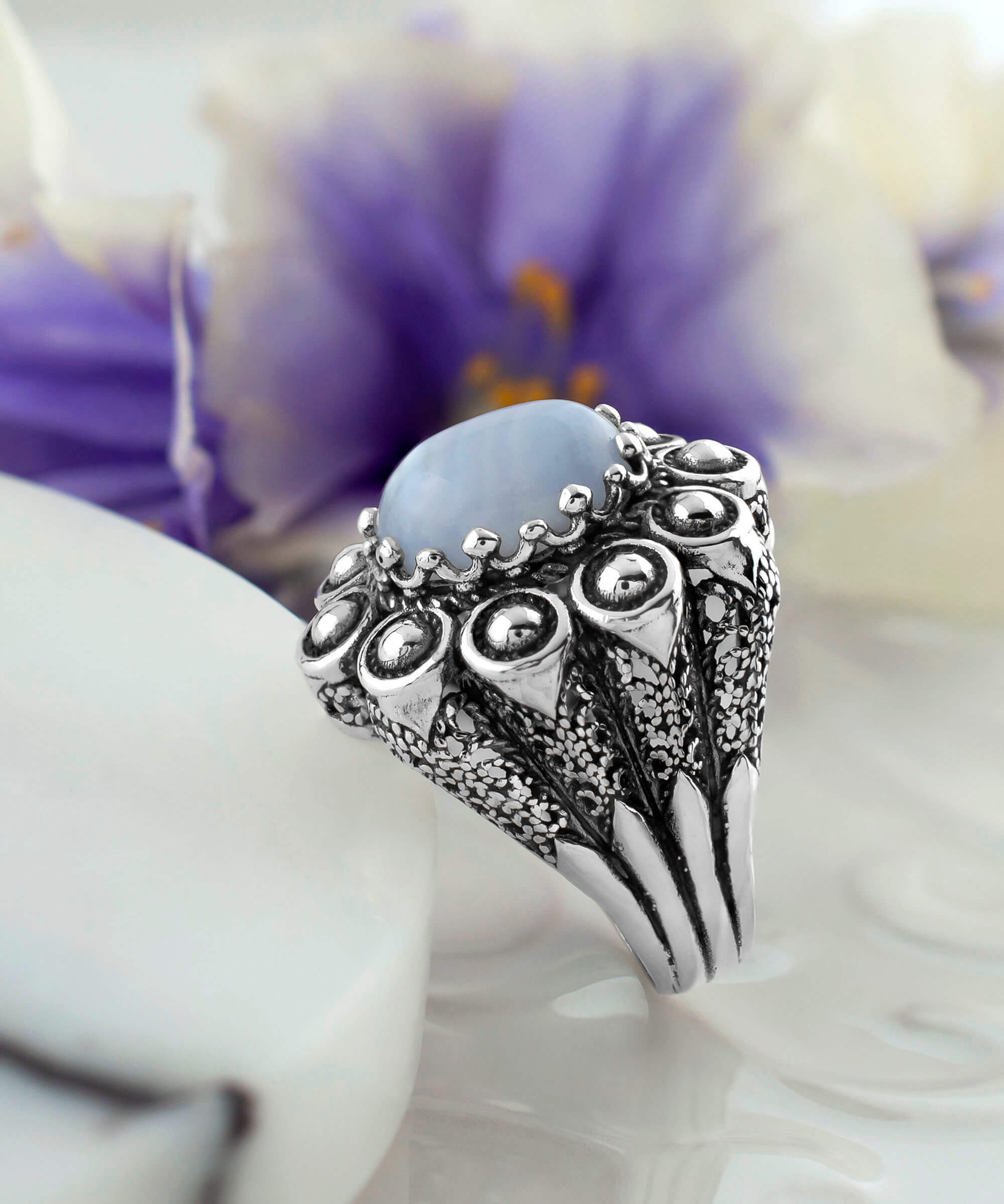 A handcrafted filigree art dome ring featuring a blue lace agate gemstone set in a 925 sterling silver band, showcasing intricate details and an antique finish.