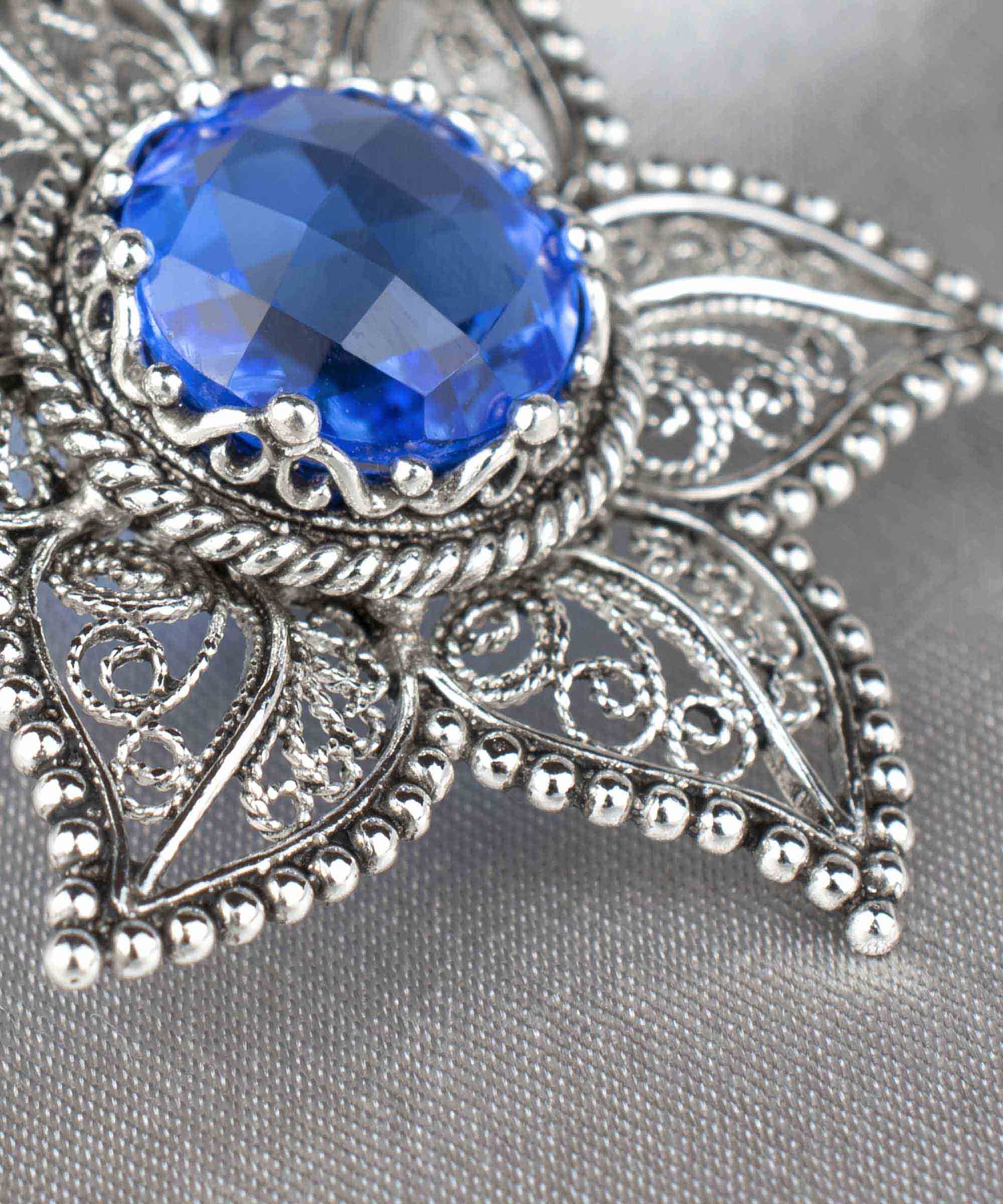 Handcrafted silver pendant featuring intricate filigree art and a blue quartz gemstone in a star design.