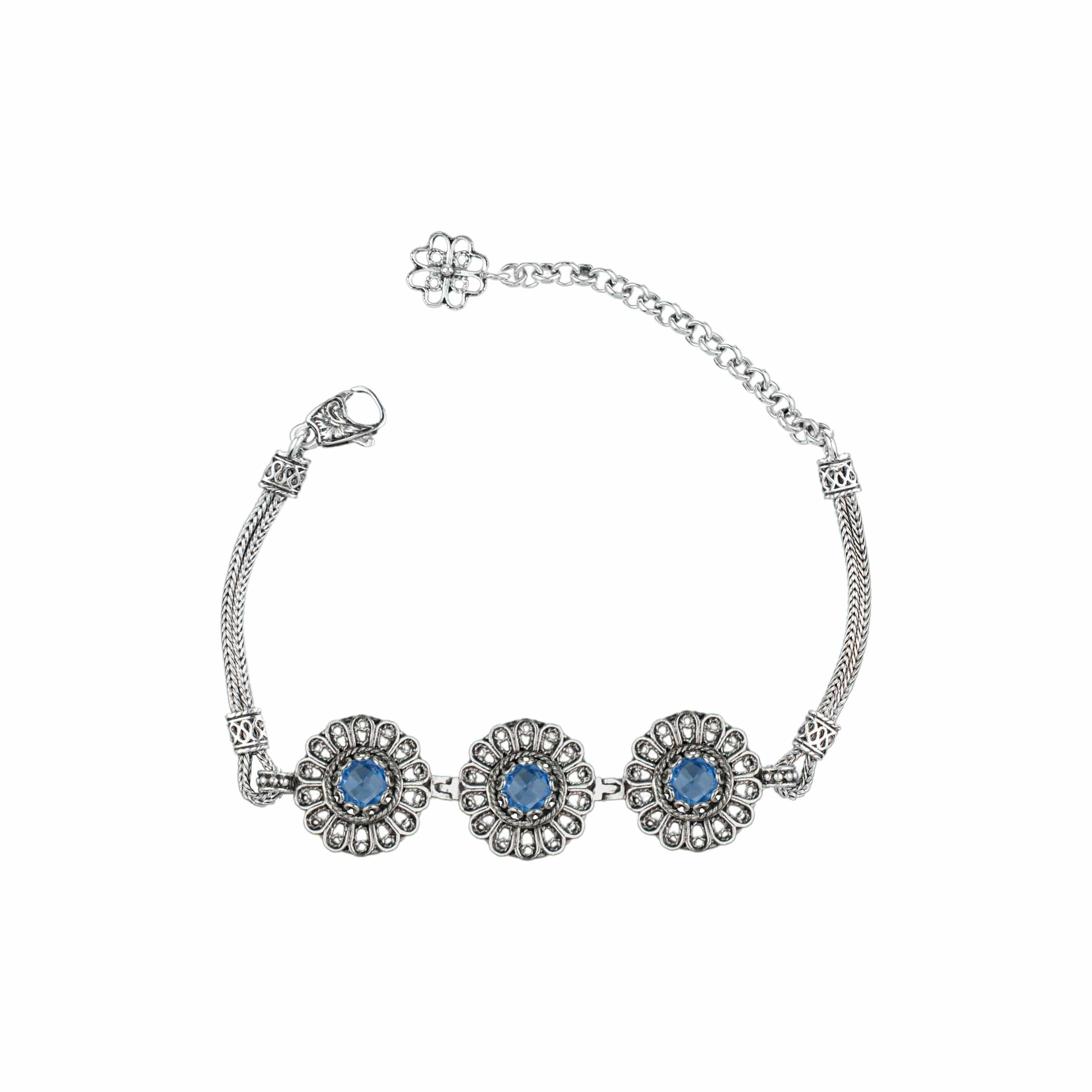 Elegant sterling silver link bracelet featuring intricate filigree art and a double-sided faceted blue quartz gemstone.