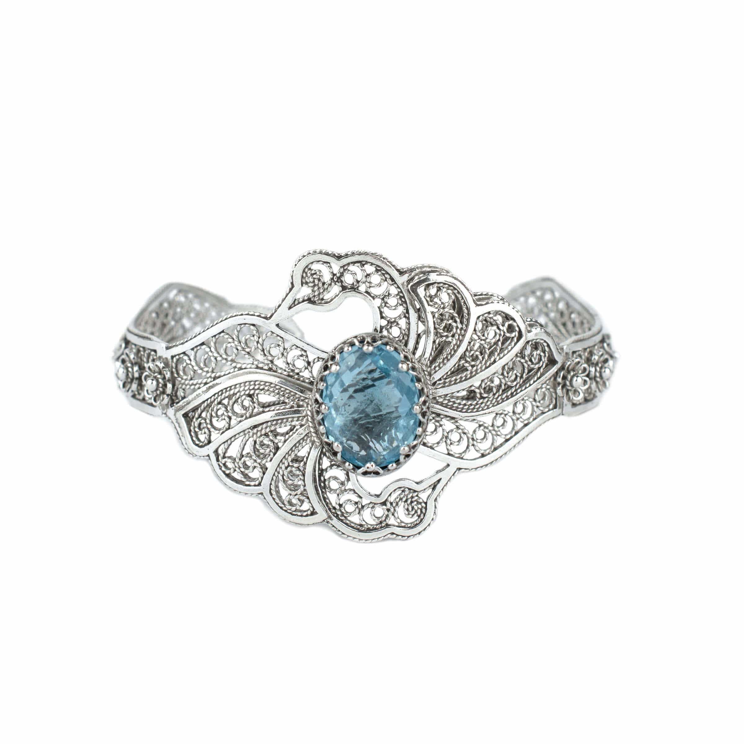 Elegant sterling silver cuff bracelet featuring intricate filigree design and a stunning blue topaz gemstone, shaped like double swans.