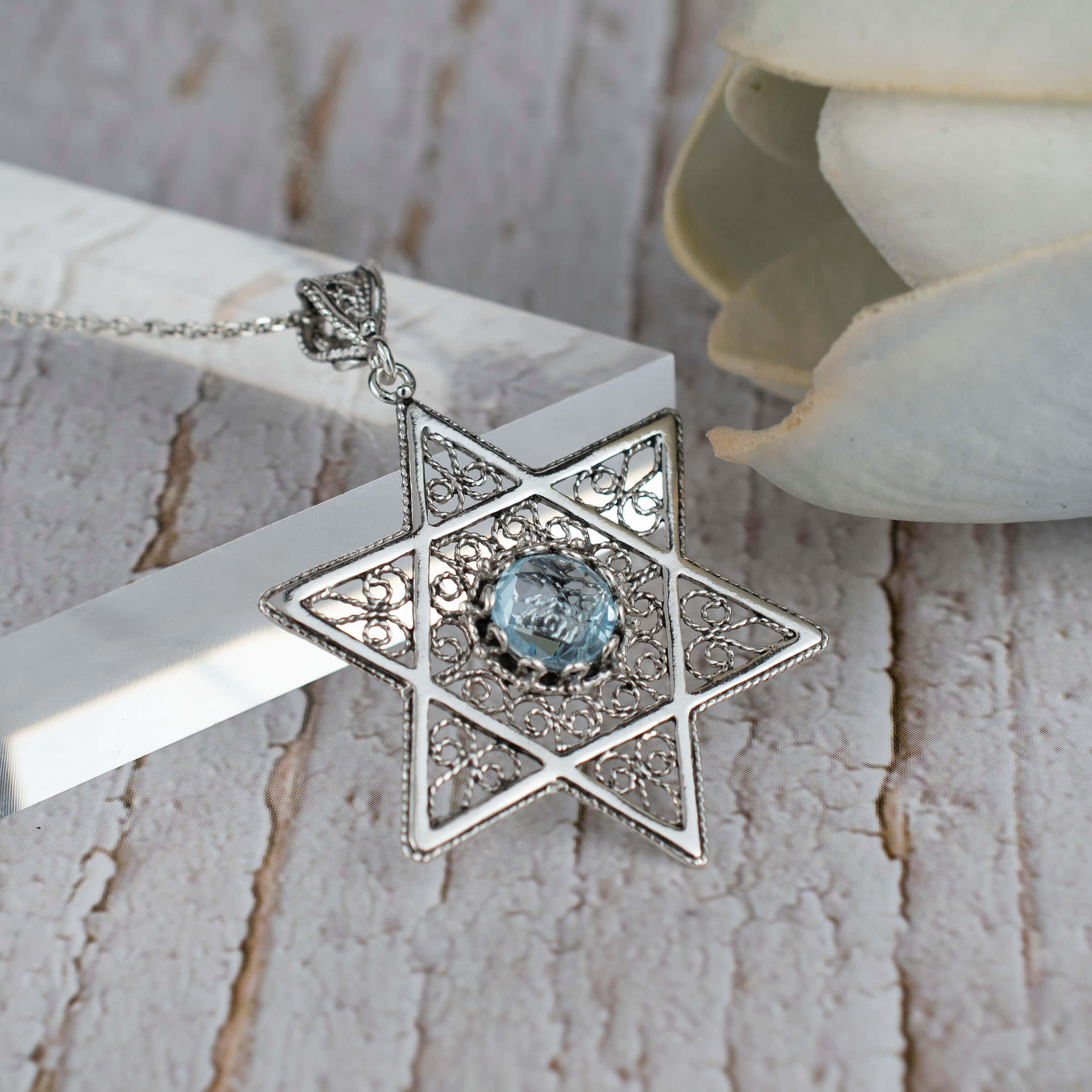 Sterling silver filigree pendant featuring a blue topaz gemstone in a Star of David design, showcasing intricate craftsmanship.