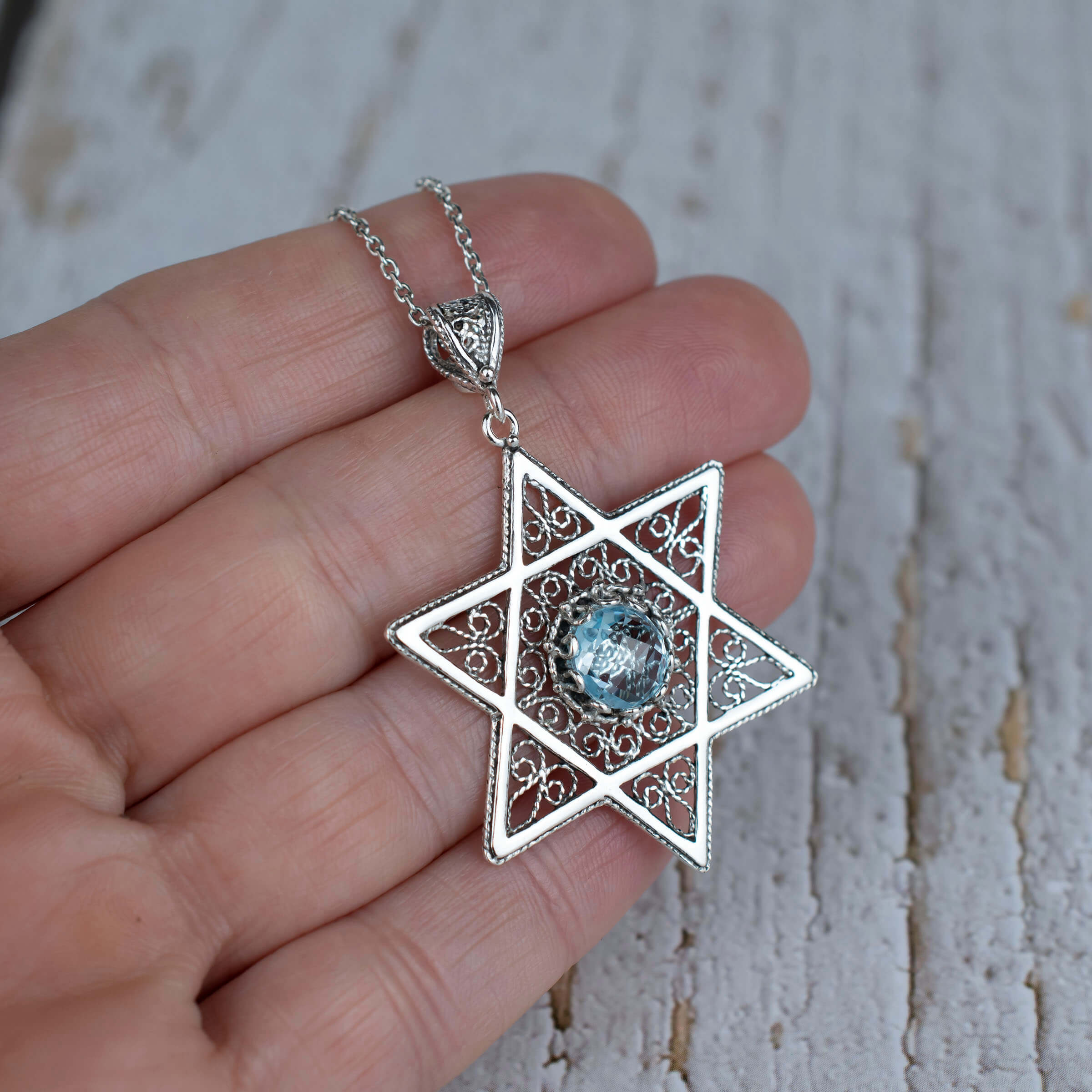 Sterling silver filigree pendant featuring a blue topaz gemstone in a Star of David design, showcasing intricate craftsmanship.