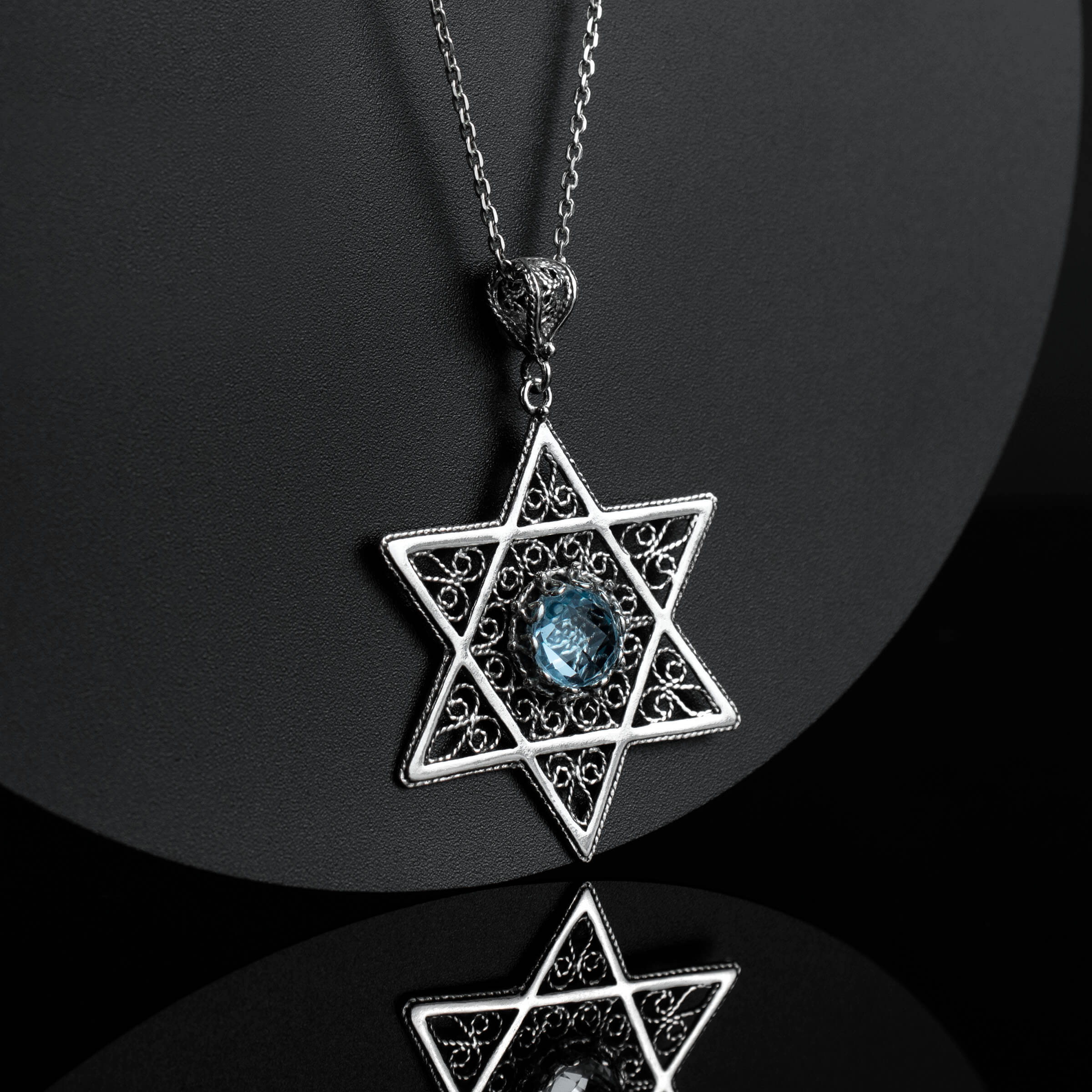 Sterling silver filigree pendant featuring a blue topaz gemstone in a Star of David design, showcasing intricate craftsmanship.